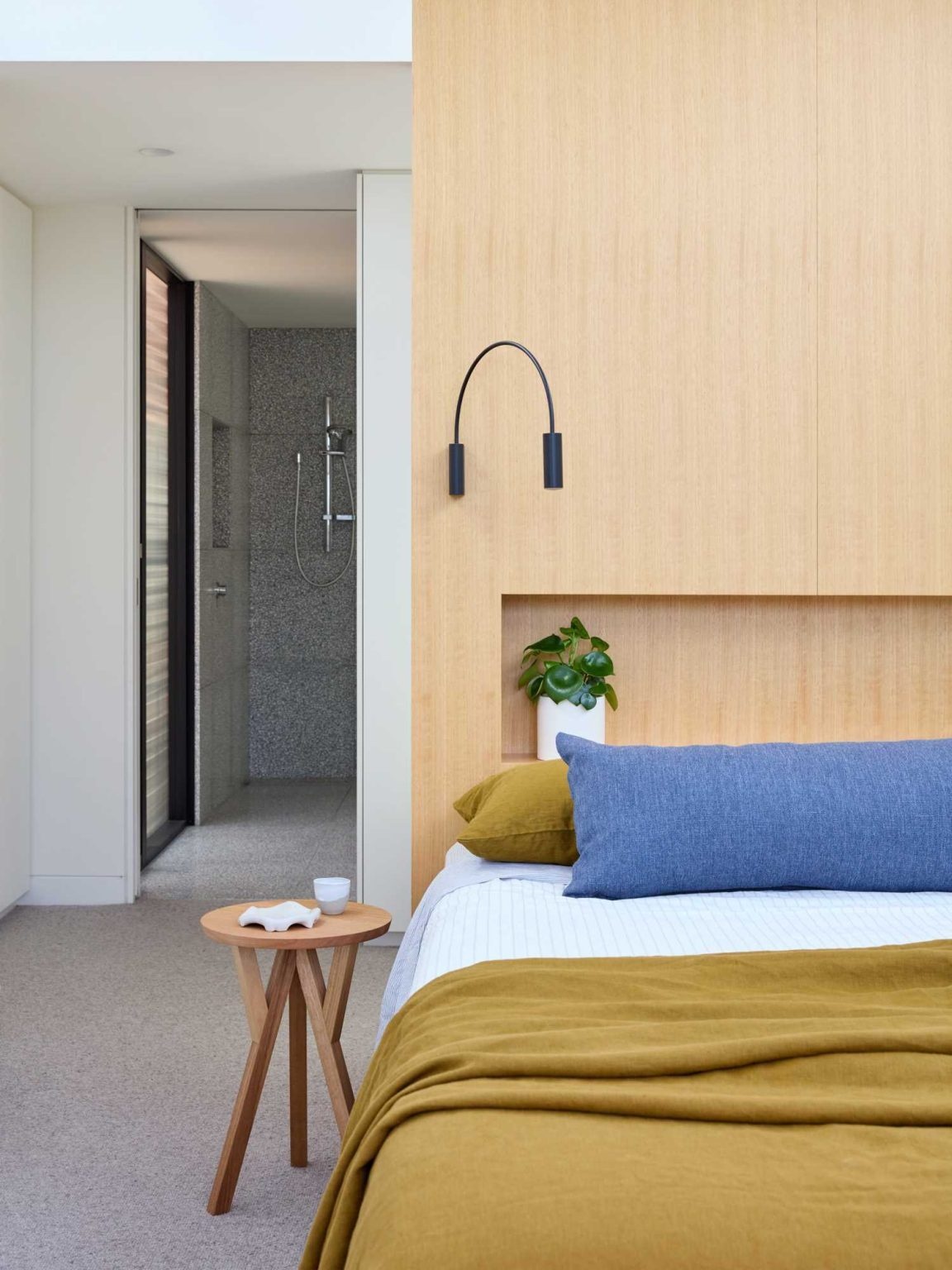 This bright bedroom combines a custom timber headboard, built-in storage and minimalist lighting beneath the extension's sculptural roofline.