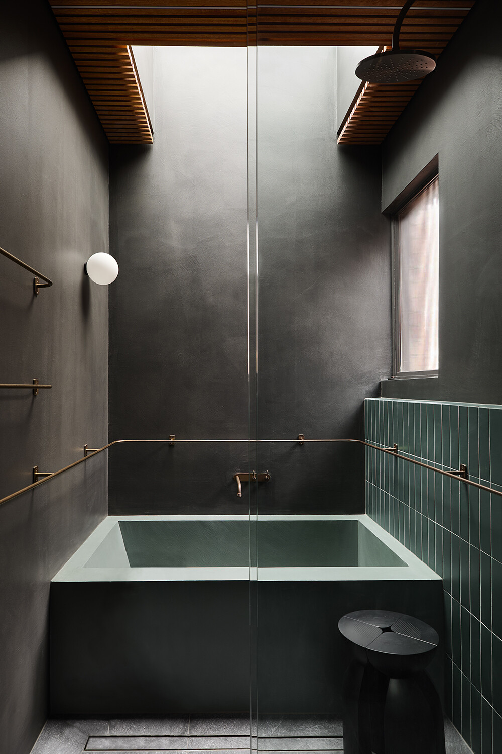 A sculpted bathroom with a microcement soaking tub and soft lighting, inspired by Japanese bathing spaces in a Melbourne home.