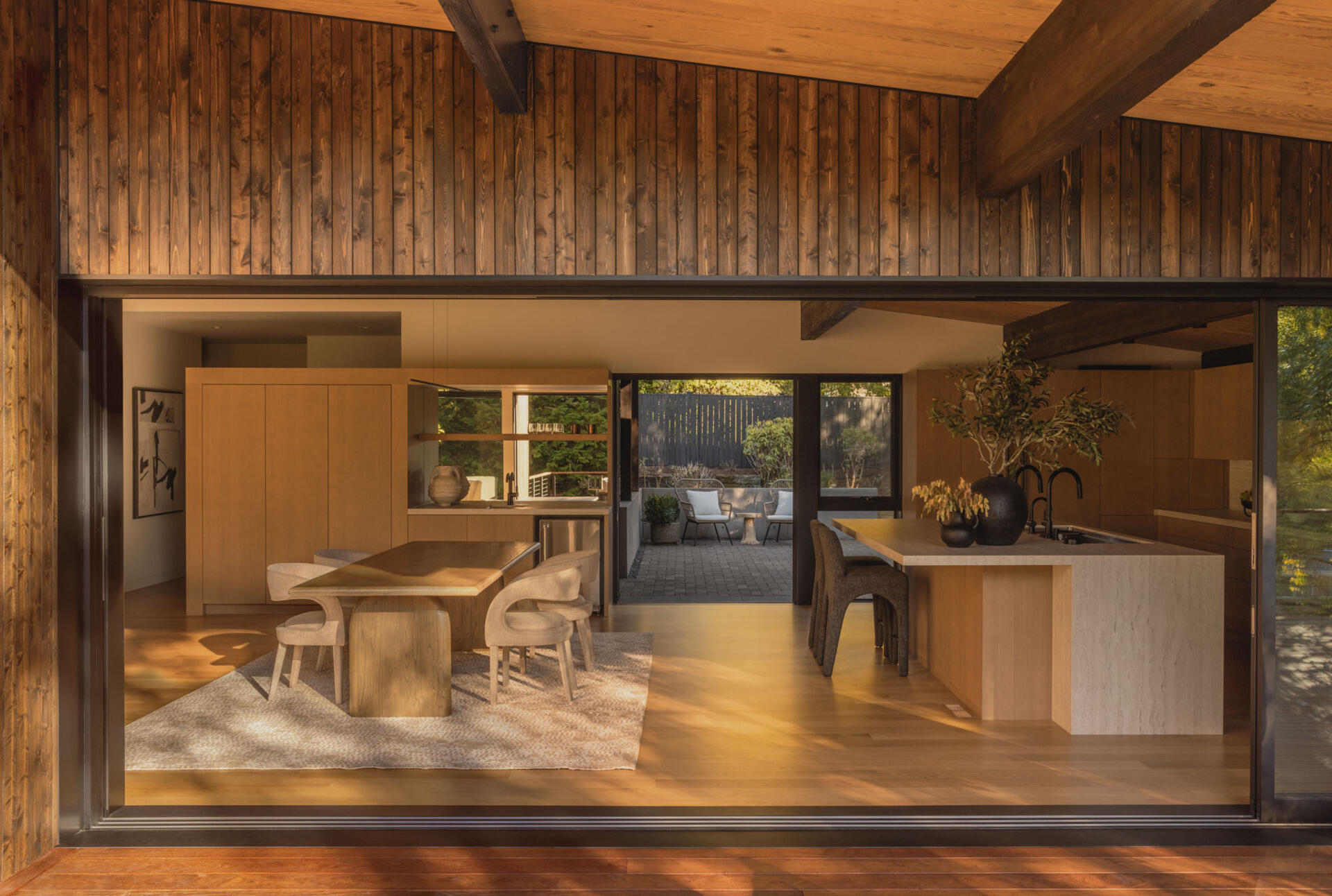 See how Island Crest's open kitchen, dining area, and expanded deck create flexible spaces for entertaining. White oak finishes, Dekton countertops, and an 18-foot sliding glass door blur the line between indoors and out.