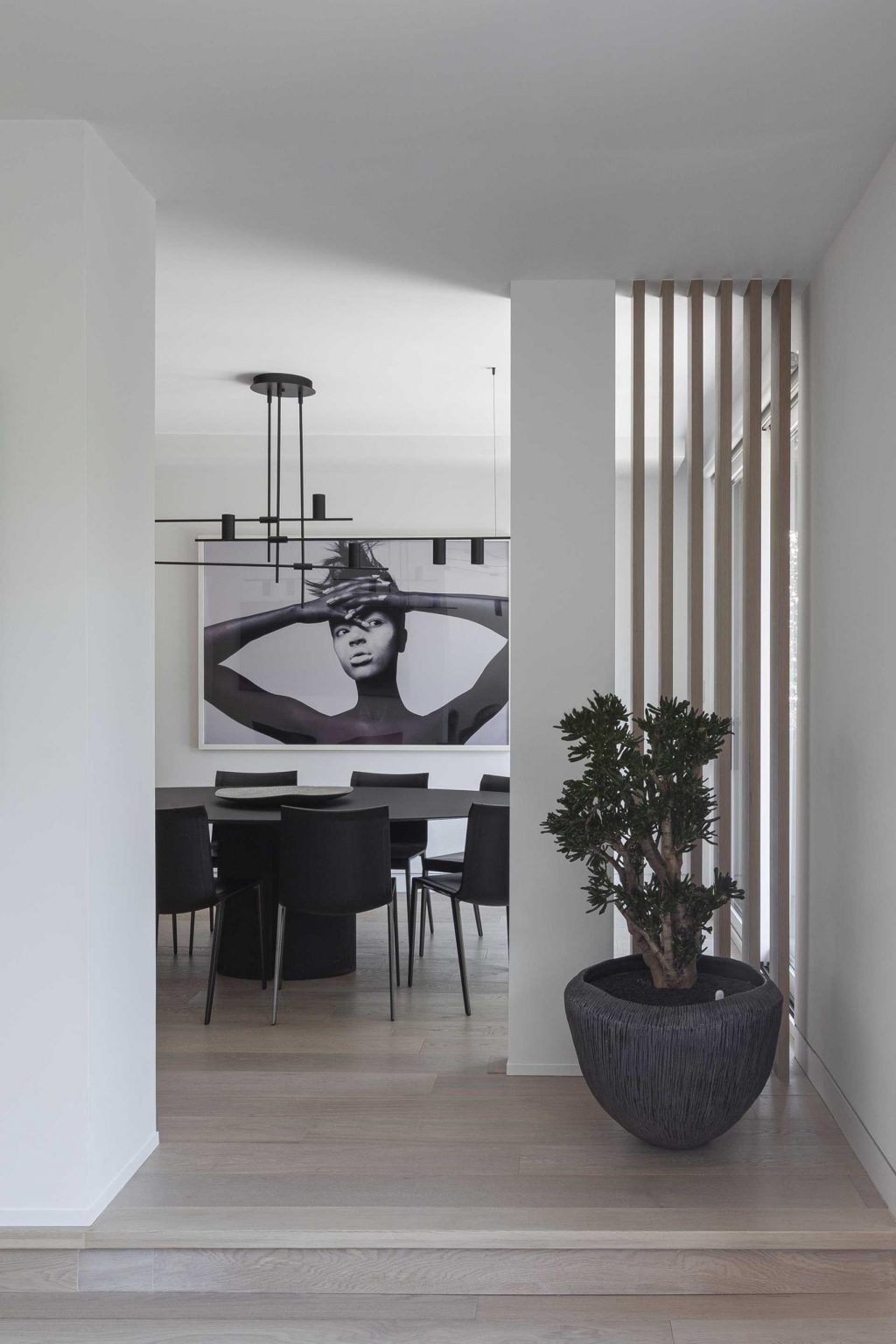 A round black dining table and minimalist pendant light create an elegant dining space that highlights the home's contemporary architecture and clean geometric forms.
