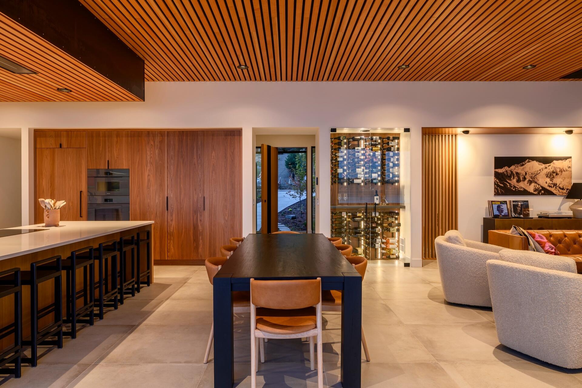 Discover a waterfront dining space where a long timber table, seamless indoor-outdoor living, and panoramic Puget Sound views create the perfect setting for entertaining.