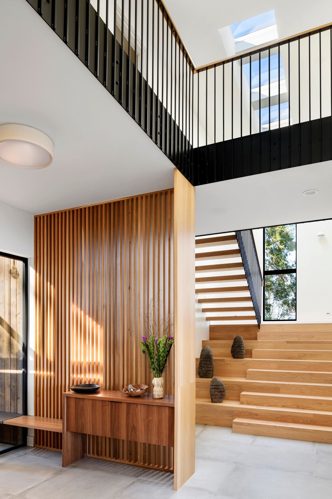 Step inside Lantern House through a light-filled entry featuring warm timber battens, a floating staircase, and beautiful modern Pacific Northwest design.
