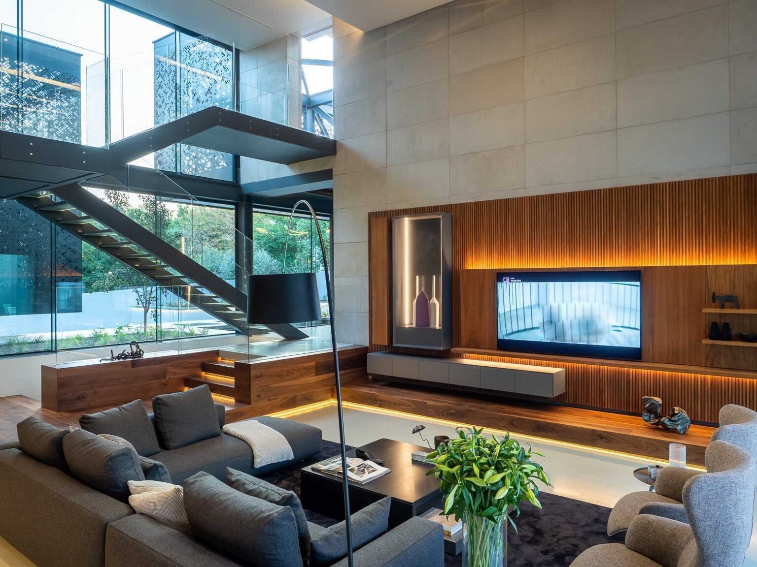 A soaring double-height ceiling, wood feature wall, hidden lighting, and pool views make the family room one of the home's standout spaces.