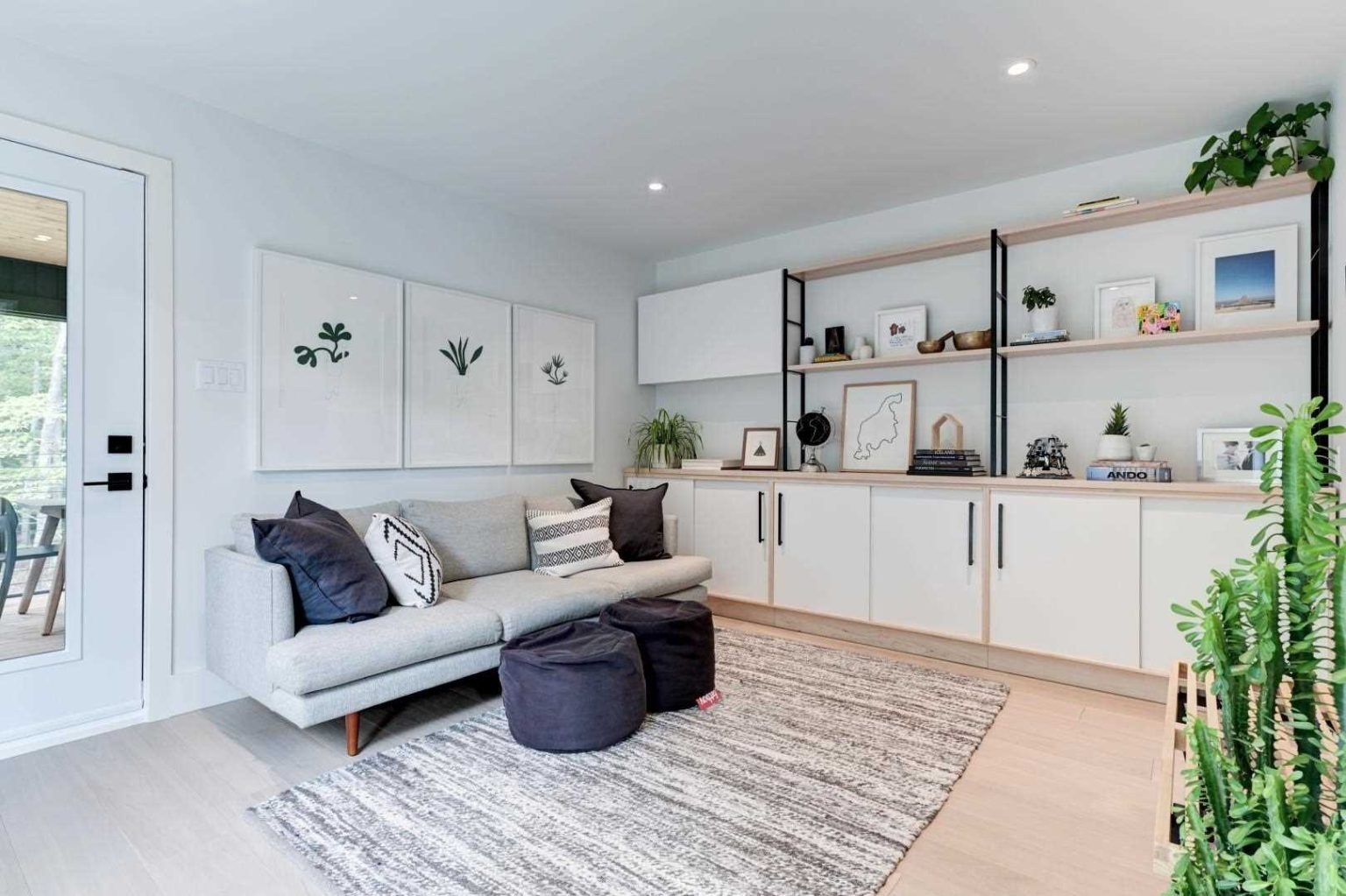 Custom cabinetry, open shelving, and greenery give this secondary living room a stylish and functional character.