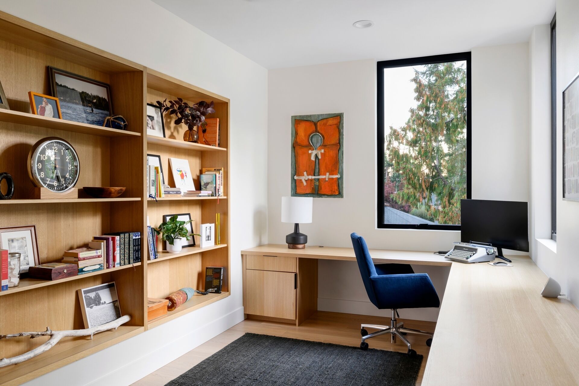The dedicated home office enjoys the same abundance of natural light found throughout the house. Positioned to overlook the surrounding landscape with its built-in corner desk, it provides a bright and comfortable place to work.