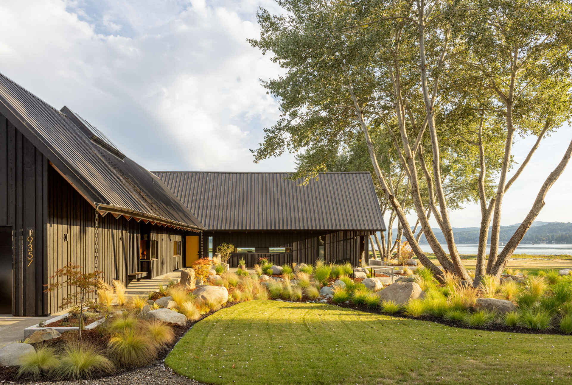 A Scandinavian-inspired waterfront home in Silverdale, Washington combines intersecting gabled forms, vaulted ceilings, and stunning views across Dyes Inlet.