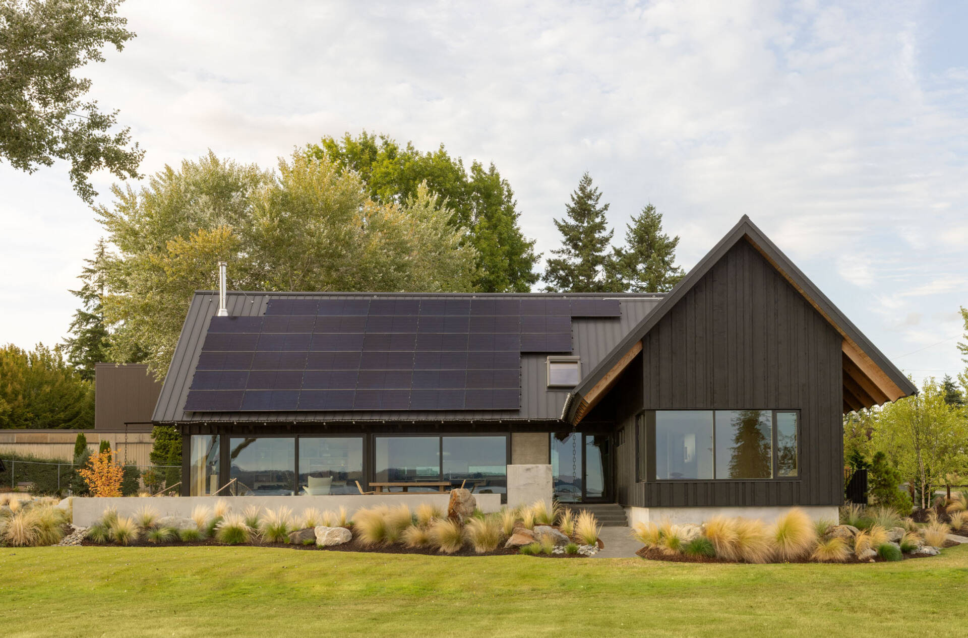A Scandinavian-inspired waterfront home in Silverdale, Washington combines intersecting gabled forms, vaulted ceilings, and stunning views across Dyes Inlet.