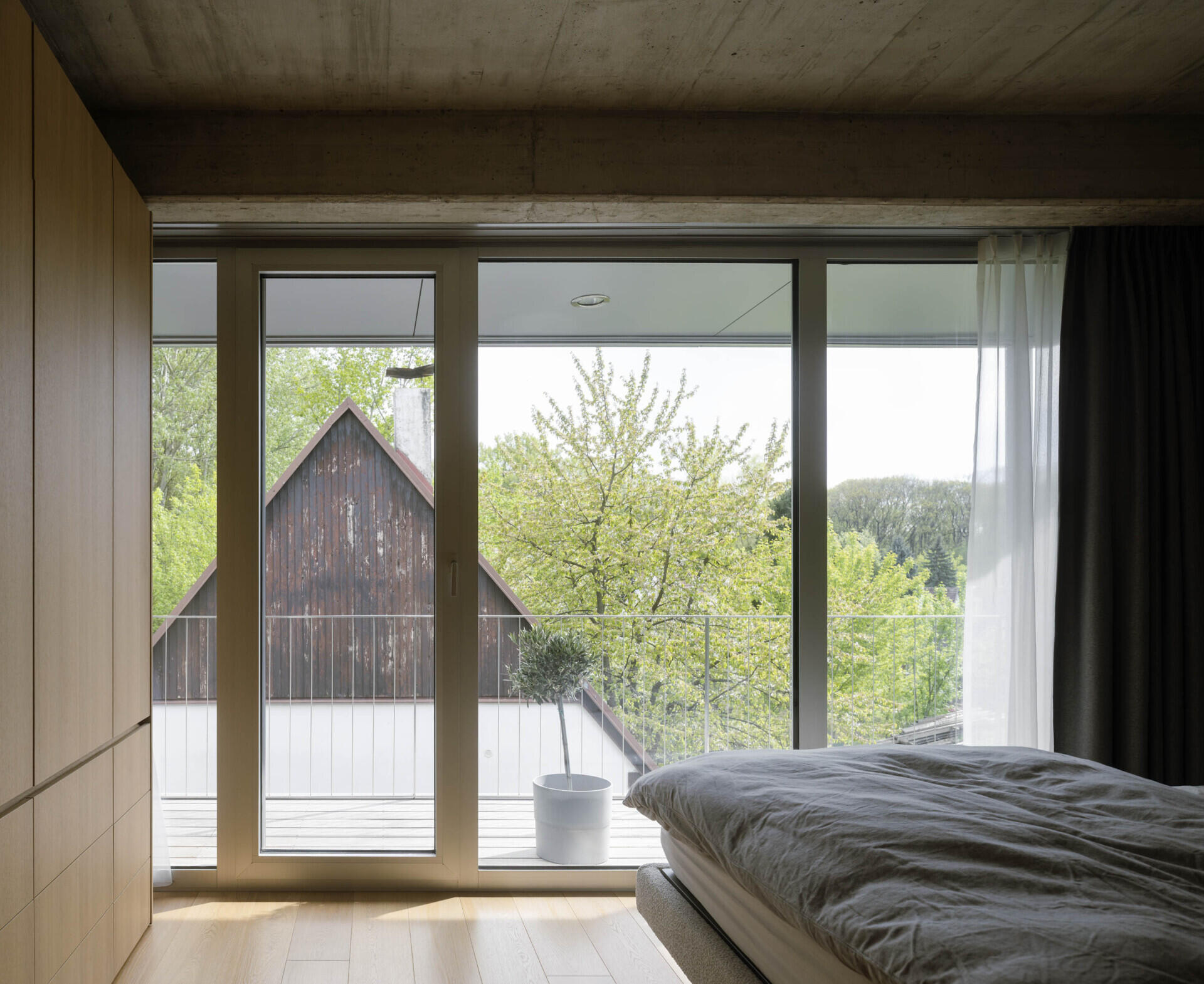 Set between the Carpathian foothills and the Danube River, this modern house features elevated living spaces, flexible interiors, panoramic views, a rooftop terrace, and a reflective raw aluminum facade that changes with the light throughout the day.