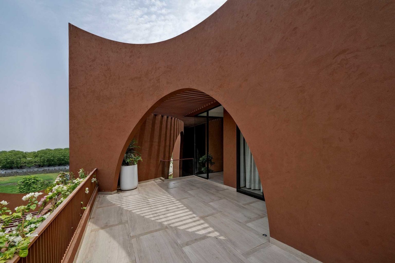 Curved patios on the upper levels extend the home’s sculptural design outdoors, creating sheltered spaces filled with light and shadow.