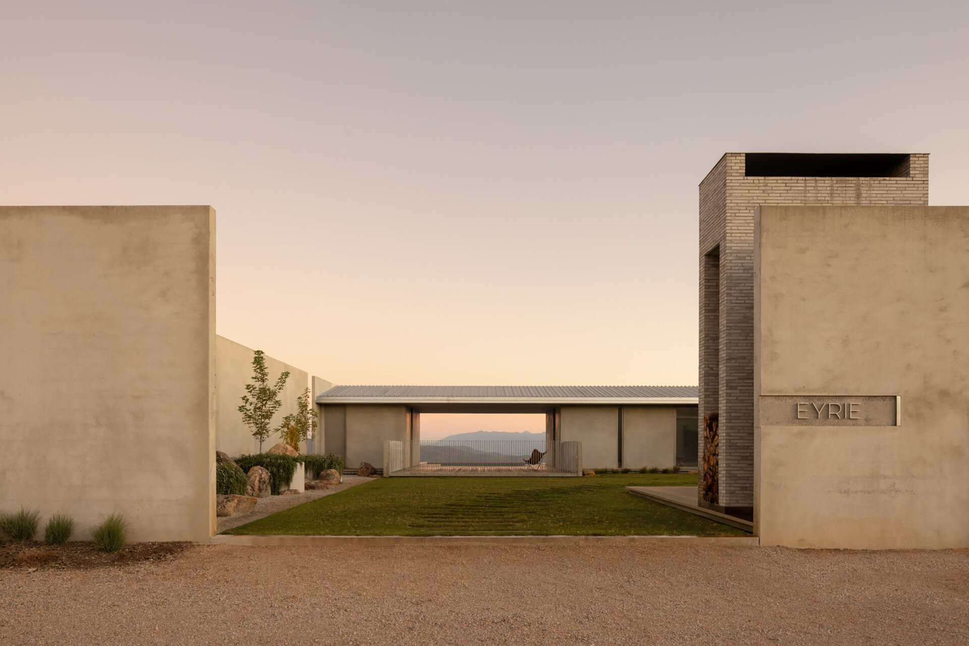 Hidden behind a concrete wall, the arrival experience at Eyrie Residence creates a dramatic reveal as visitors discover the courtyard beyond.