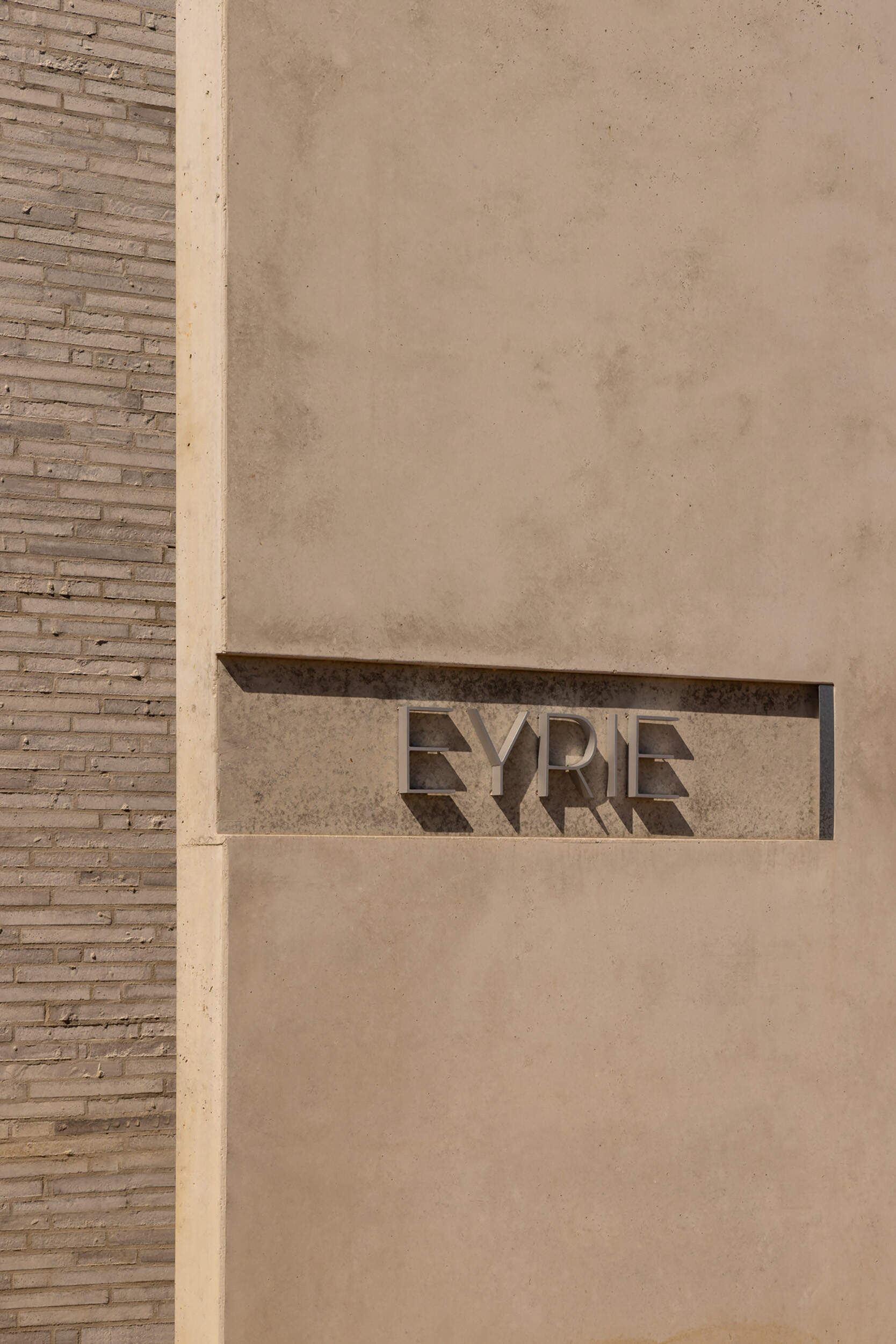 Hidden behind a concrete wall, the arrival experience at Eyrie Residence creates a dramatic reveal as visitors discover the courtyard beyond.