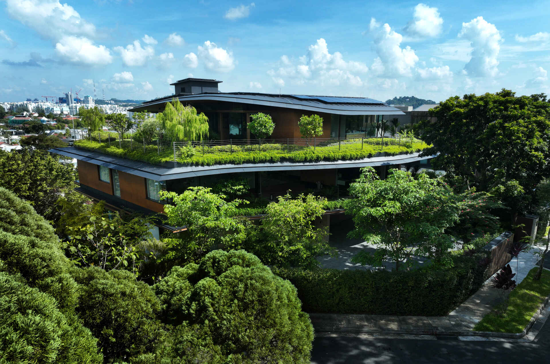 A multi-generational home filled with terraced gardens, rooftop lawns, reflecting ponds, and breathtaking city views. Warm timber interiors, tropical landscaping, open-air walkways, and a lagoon-like pool create a beautiful blend of architecture and nature.