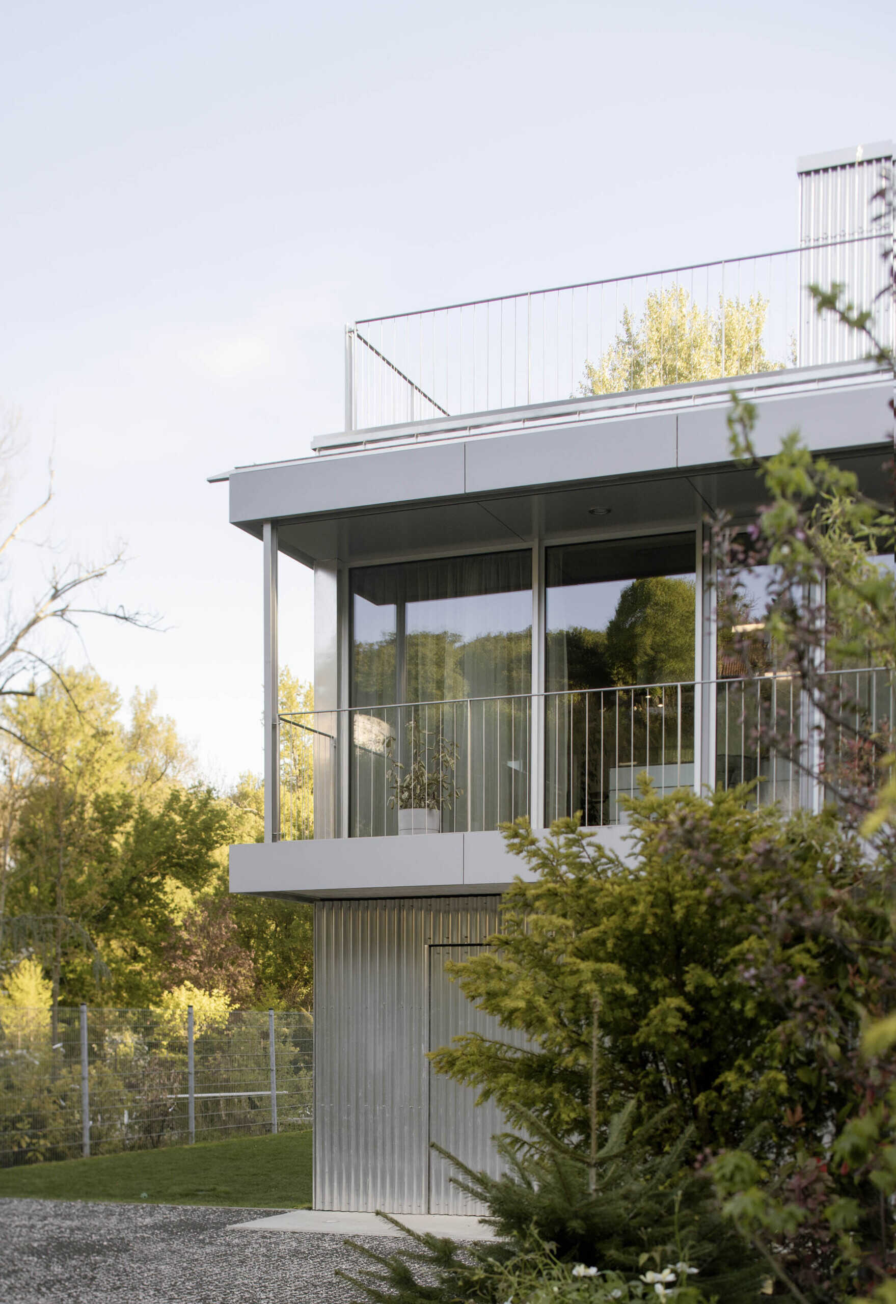 Set between the Carpathian foothills and the Danube River, this modern house features elevated living spaces, flexible interiors, panoramic views, a rooftop terrace, and a reflective raw aluminum facade that changes with the light throughout the day.