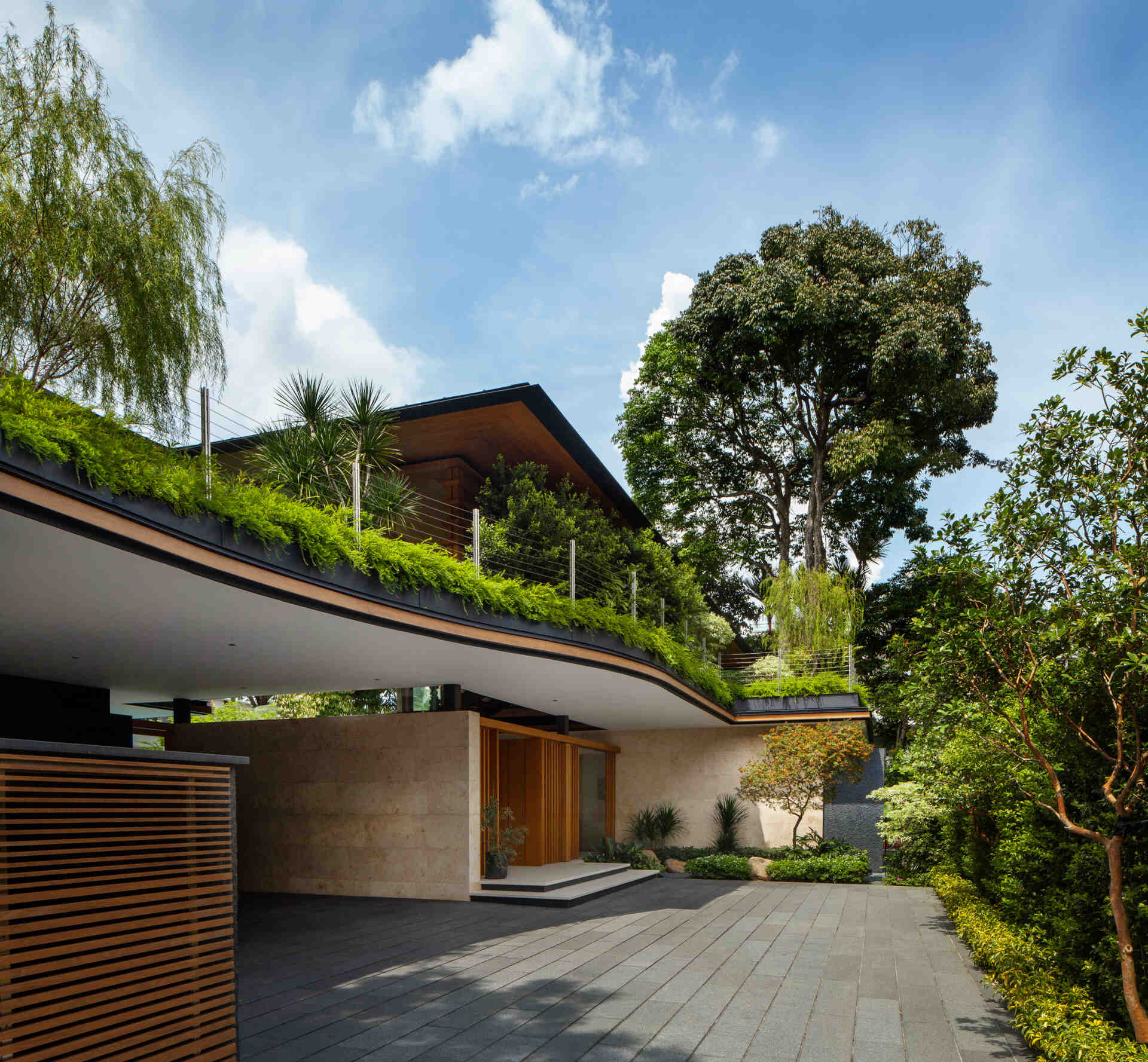 A tropical residence designed around a private courtyard garden. Featuring warm timber interiors, dramatic rooflines, a long swimming pool, lush landscaping, glass walls, and a sculptural spiral staircase, this modern home showcases the beauty of indoor-outdoor living in a tropical climate.