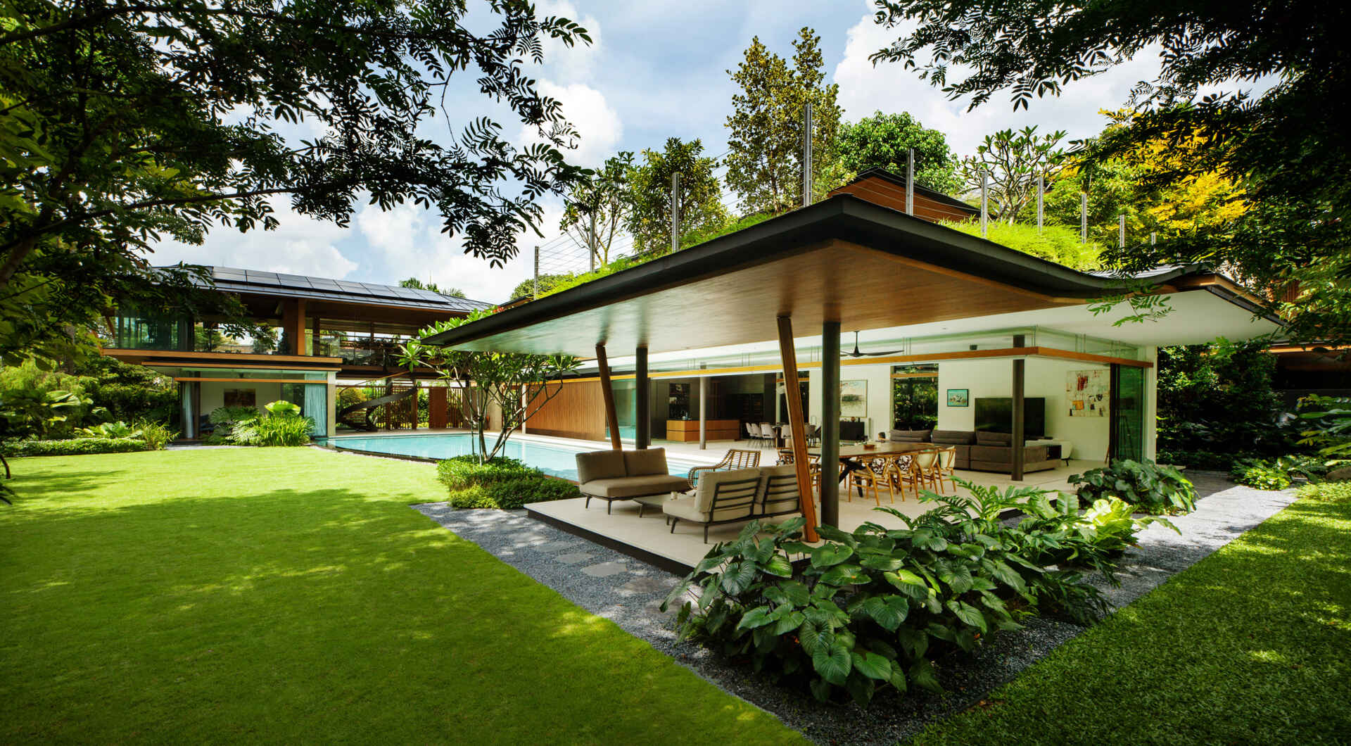 A tropical residence designed around a private courtyard garden. Featuring warm timber interiors, dramatic rooflines, a long swimming pool, lush landscaping, glass walls, and a sculptural spiral staircase, this modern home showcases the beauty of indoor-outdoor living in a tropical climate.