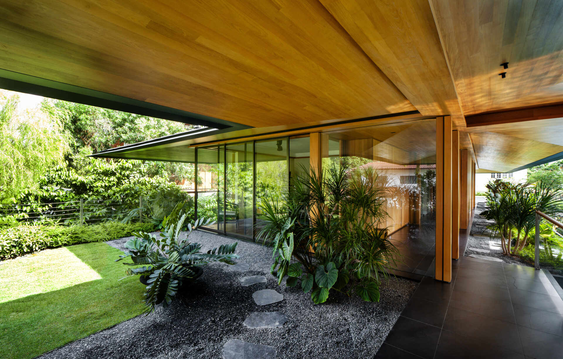A tropical residence designed around a private courtyard garden. Featuring warm timber interiors, dramatic rooflines, a long swimming pool, lush landscaping, glass walls, and a sculptural spiral staircase, this modern home showcases the beauty of indoor-outdoor living in a tropical climate.