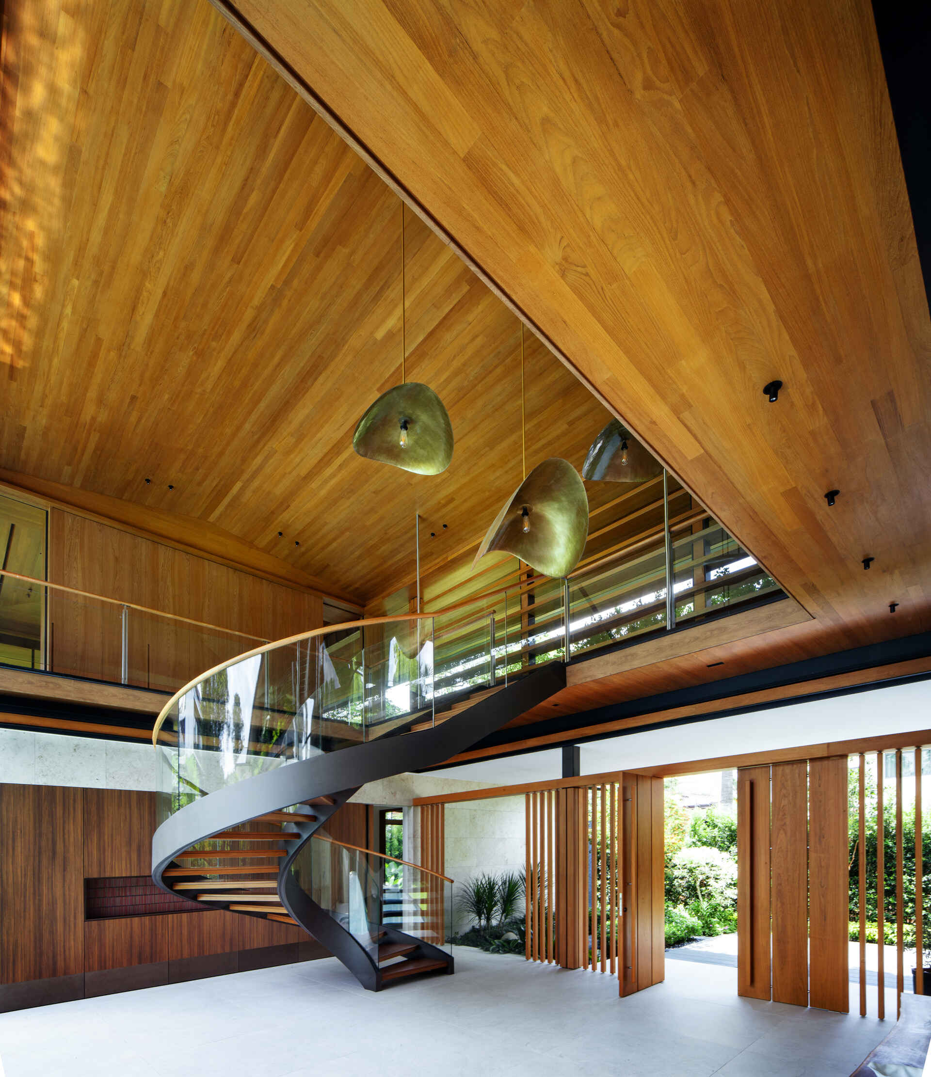A tropical residence designed around a private courtyard garden. Featuring warm timber interiors, dramatic rooflines, a long swimming pool, lush landscaping, glass walls, and a sculptural spiral staircase, this modern home showcases the beauty of indoor-outdoor living in a tropical climate.