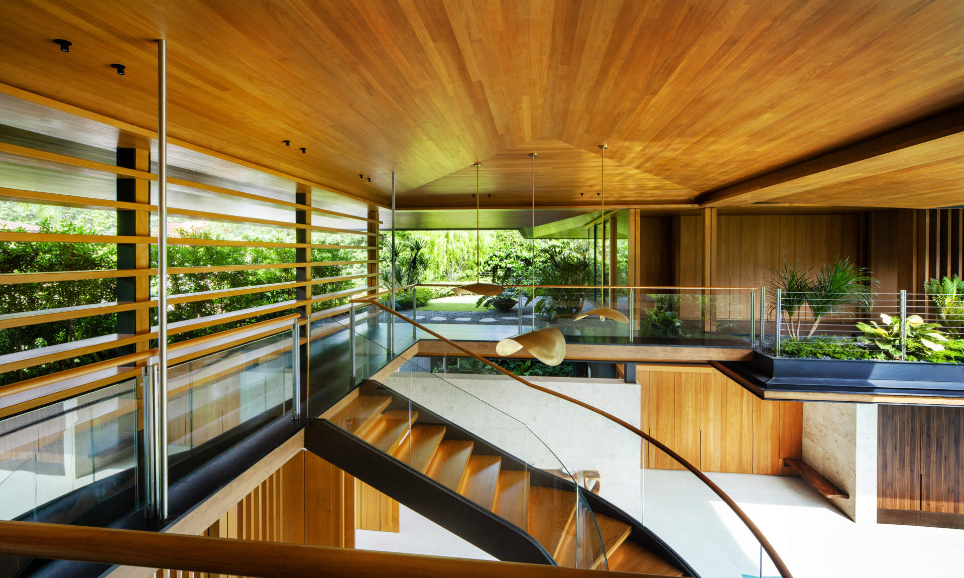 A tropical residence designed around a private courtyard garden. Featuring warm timber interiors, dramatic rooflines, a long swimming pool, lush landscaping, glass walls, and a sculptural spiral staircase, this modern home showcases the beauty of indoor-outdoor living in a tropical climate.
