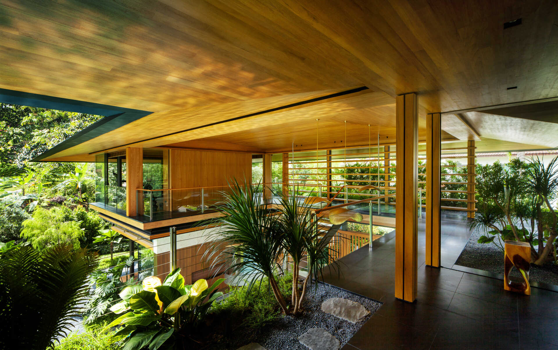A tropical residence designed around a private courtyard garden. Featuring warm timber interiors, dramatic rooflines, a long swimming pool, lush landscaping, glass walls, and a sculptural spiral staircase, this modern home showcases the beauty of indoor-outdoor living in a tropical climate.