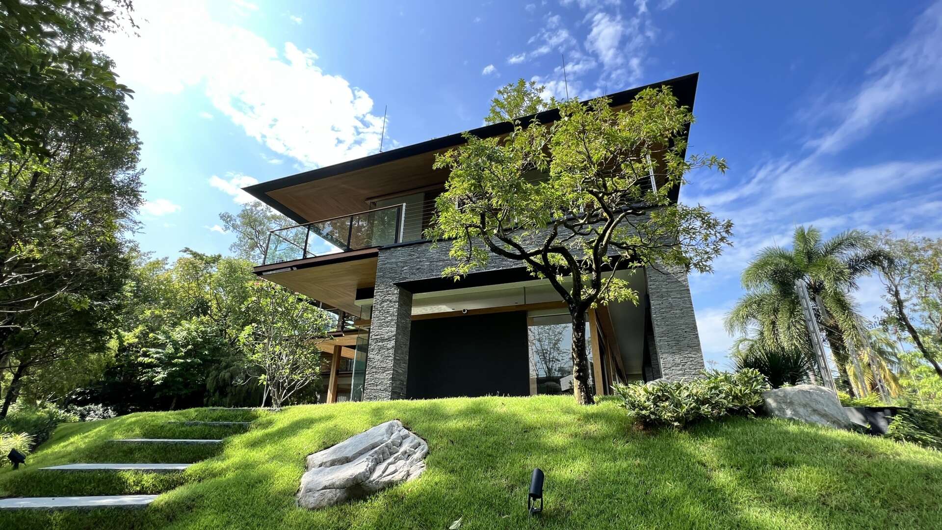 Sky Pavilion House by Guz Architects transforms an unusual Singapore site into a lush garden-focused home with a rooftop pavilion, glass staircase, swimming pool, and smart passive cooling features. Discover how greenery, natural breezes, and tropical design come together in this stunning residence.