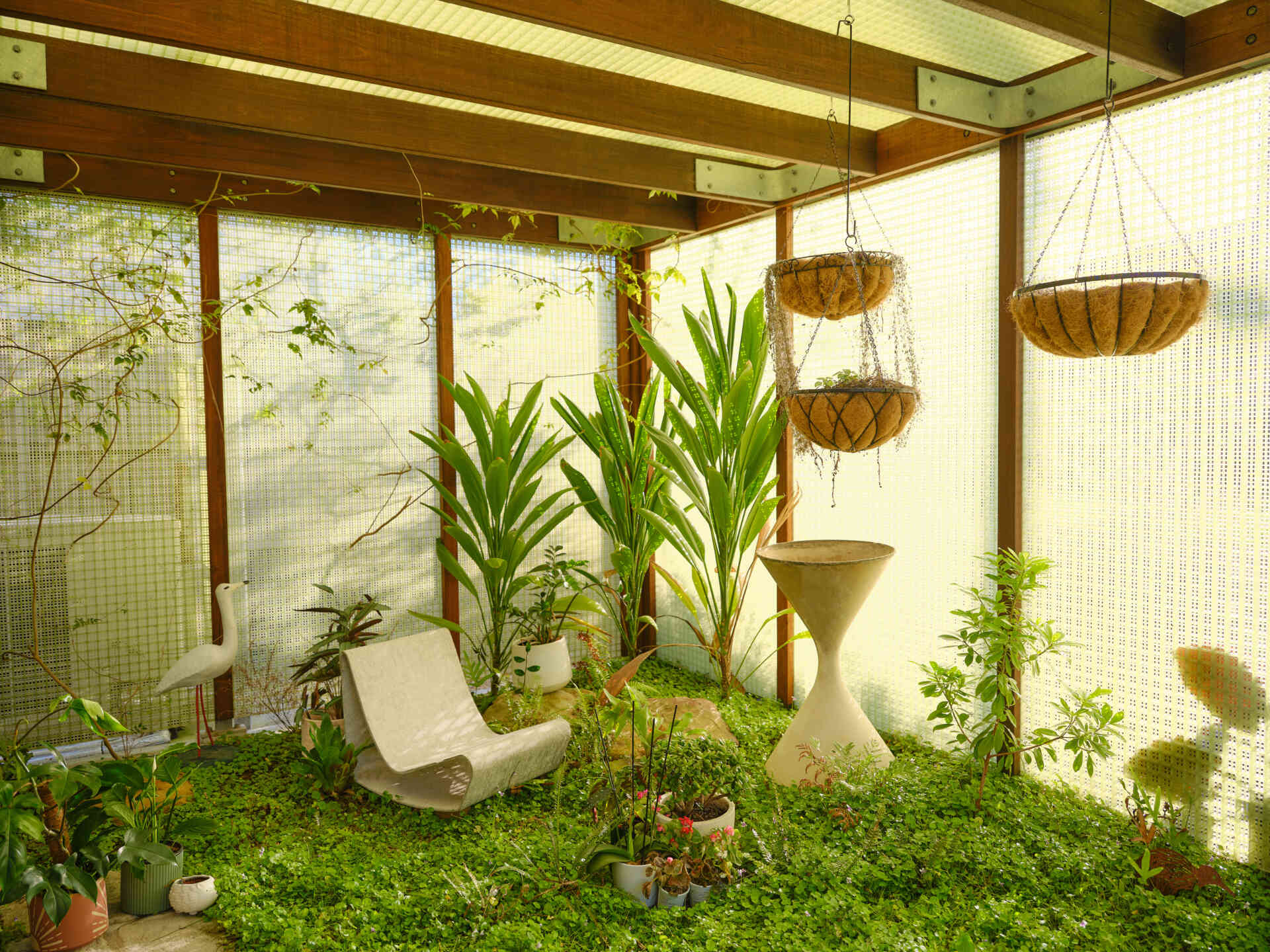 This garden entry path winds through lush planting and translucent screens, creating a welcoming arrival experience filled with greenery and filtered light.