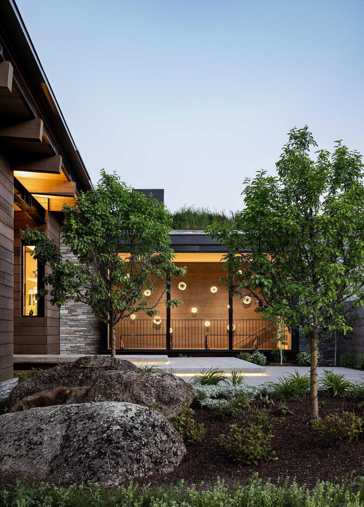 A floating bridge suspended above a dry creek bed creates a dramatic arrival experience, leading into a home defined by exposed timber, steel, stone, and breathtaking valley views.