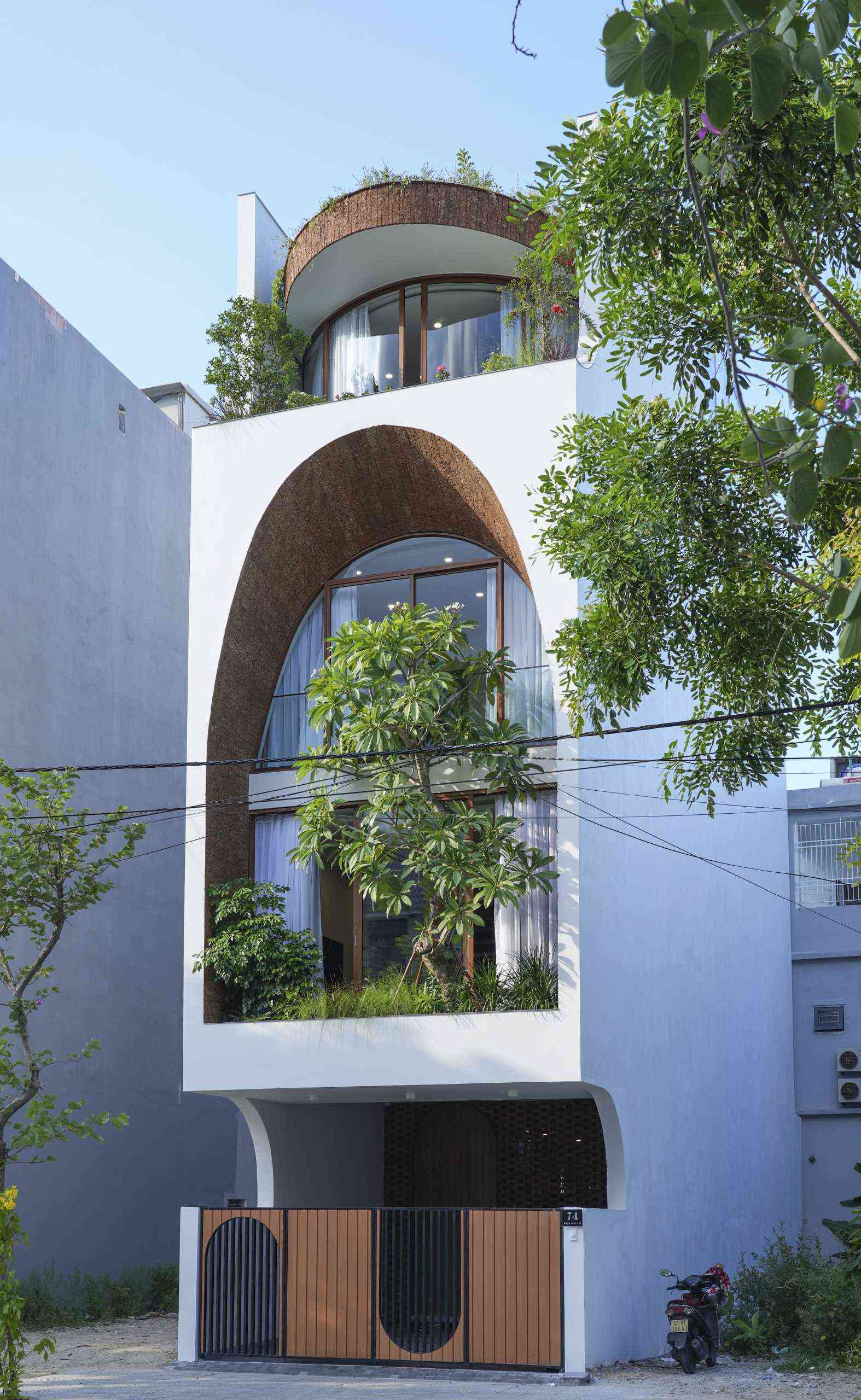 A giant arched facade gives this modern Vietnam house its signature look while helping bring daylight into the interior and creating a lantern-like glow at night.