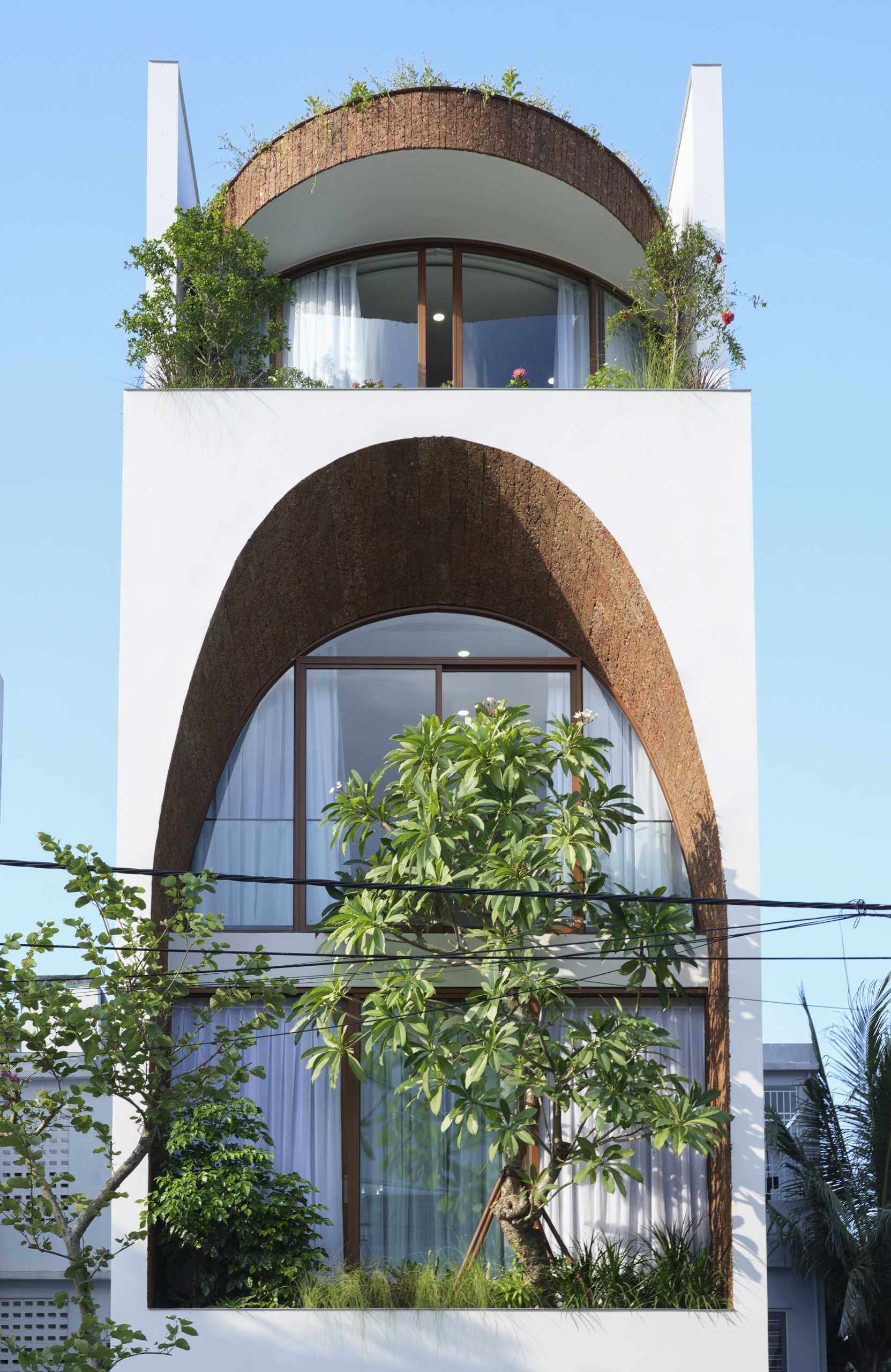 A giant arched facade gives this modern Vietnam house its signature look while helping bring daylight into the interior and creating a lantern-like glow at night.