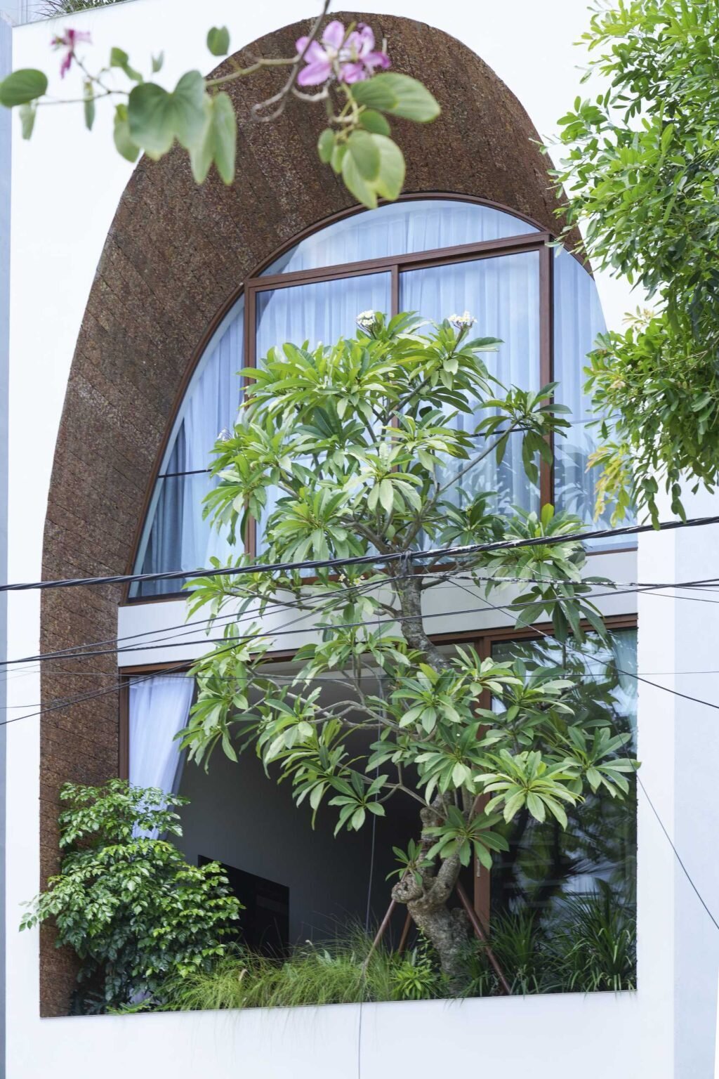 A giant arched facade gives this modern Vietnam house its signature look while helping bring daylight into the interior and creating a lantern-like glow at night.
