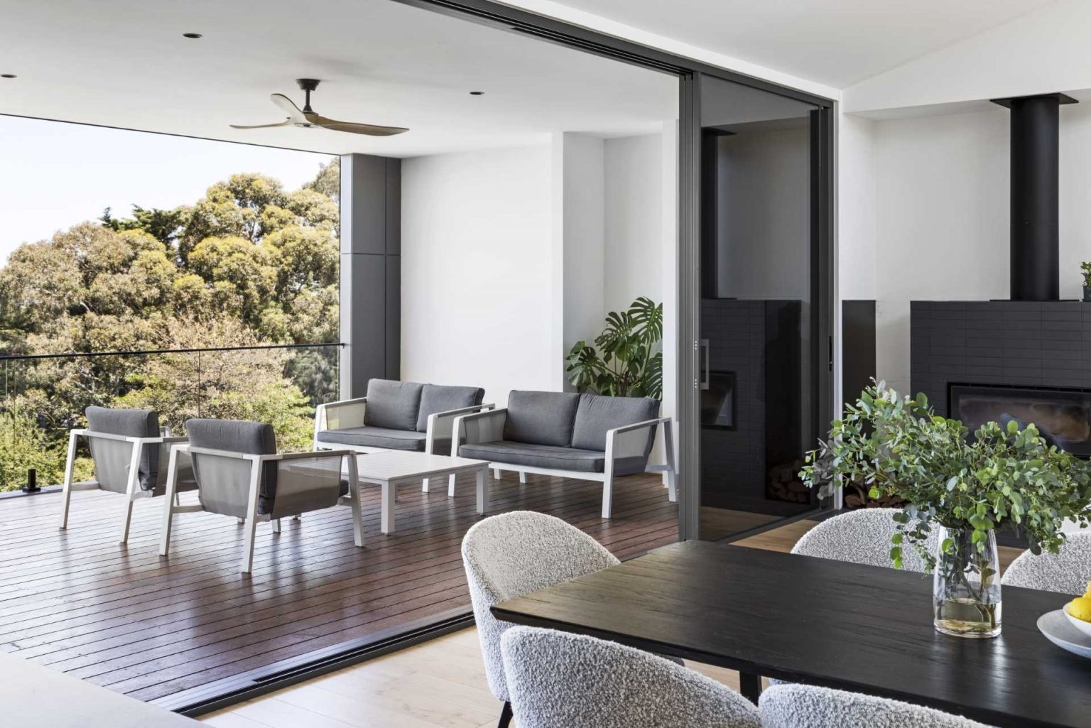 Large openings connect the living spaces to a covered deck overlooking bushland, creating an ideal setting for entertaining and relaxing.