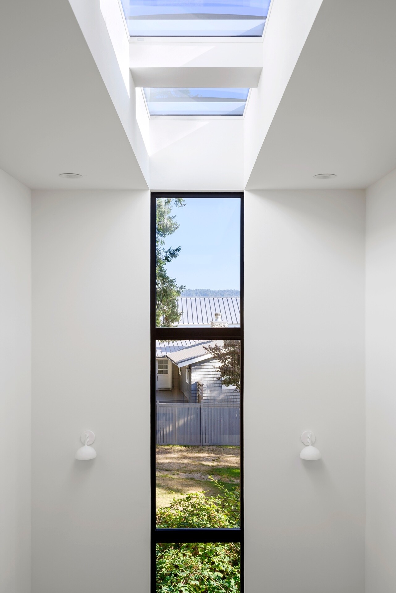 The staircase benefits from the home's double-height design, allowing daylight from above and the windows brightening both levels. It creates an open transition between floors while reinforcing the home's light-filled atmosphere.