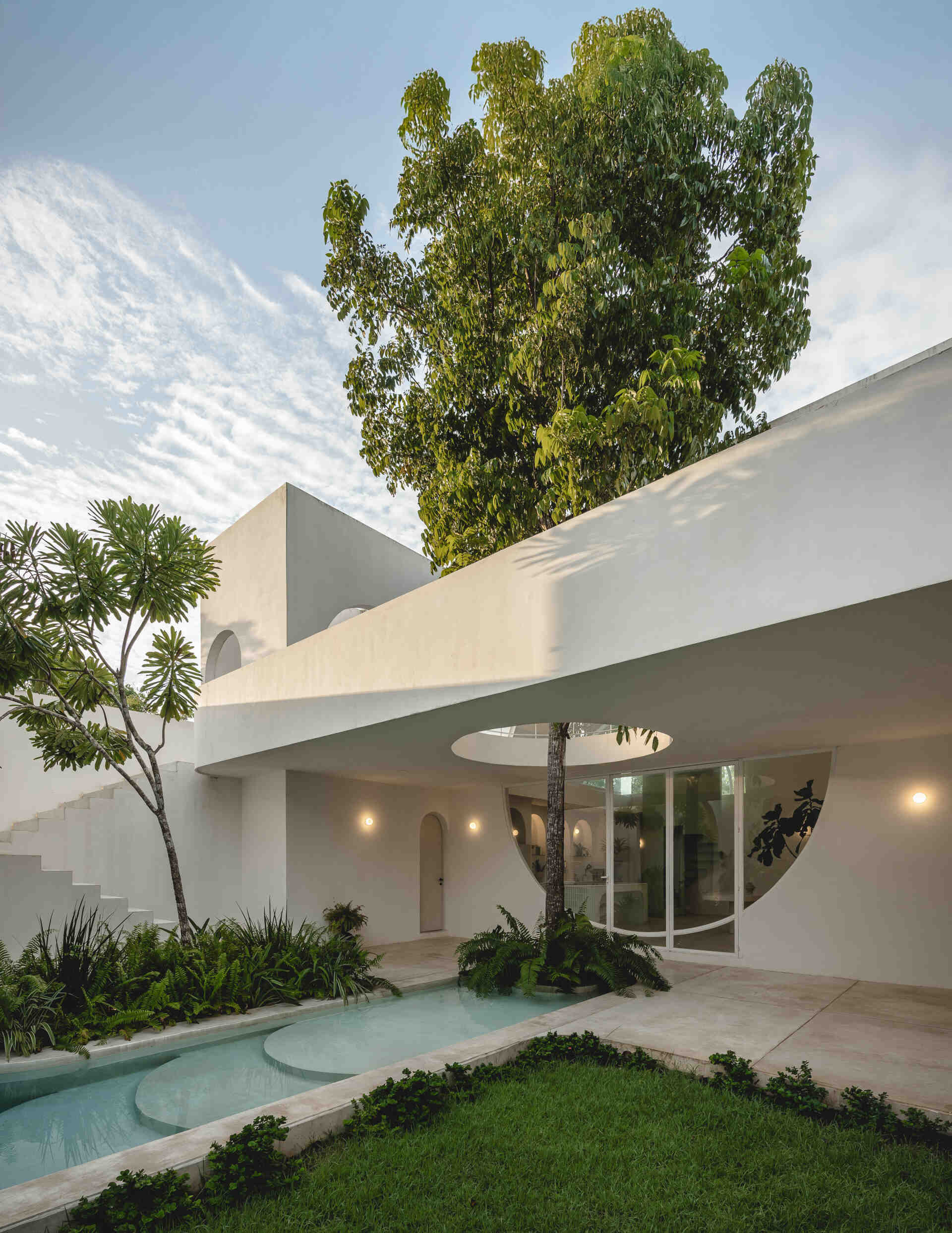 Eclipse House in Mérida, Mexico, is a striking exploration of geometry, light, and landscape. Designed by Etea and Ghostframe, the home features a dramatic double-height gallery, arch-lined walkways, circular openings that inspired its name, and lush gardens woven throughout the architecture.
