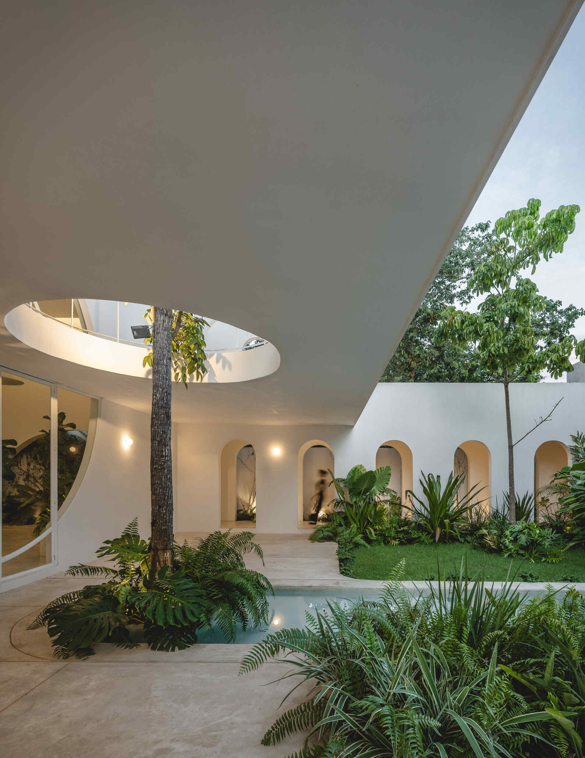 Eclipse House in Mérida, Mexico, is a striking exploration of geometry, light, and landscape. Designed by Etea and Ghostframe, the home features a dramatic double-height gallery, arch-lined walkways, circular openings that inspired its name, and lush gardens woven throughout the architecture.