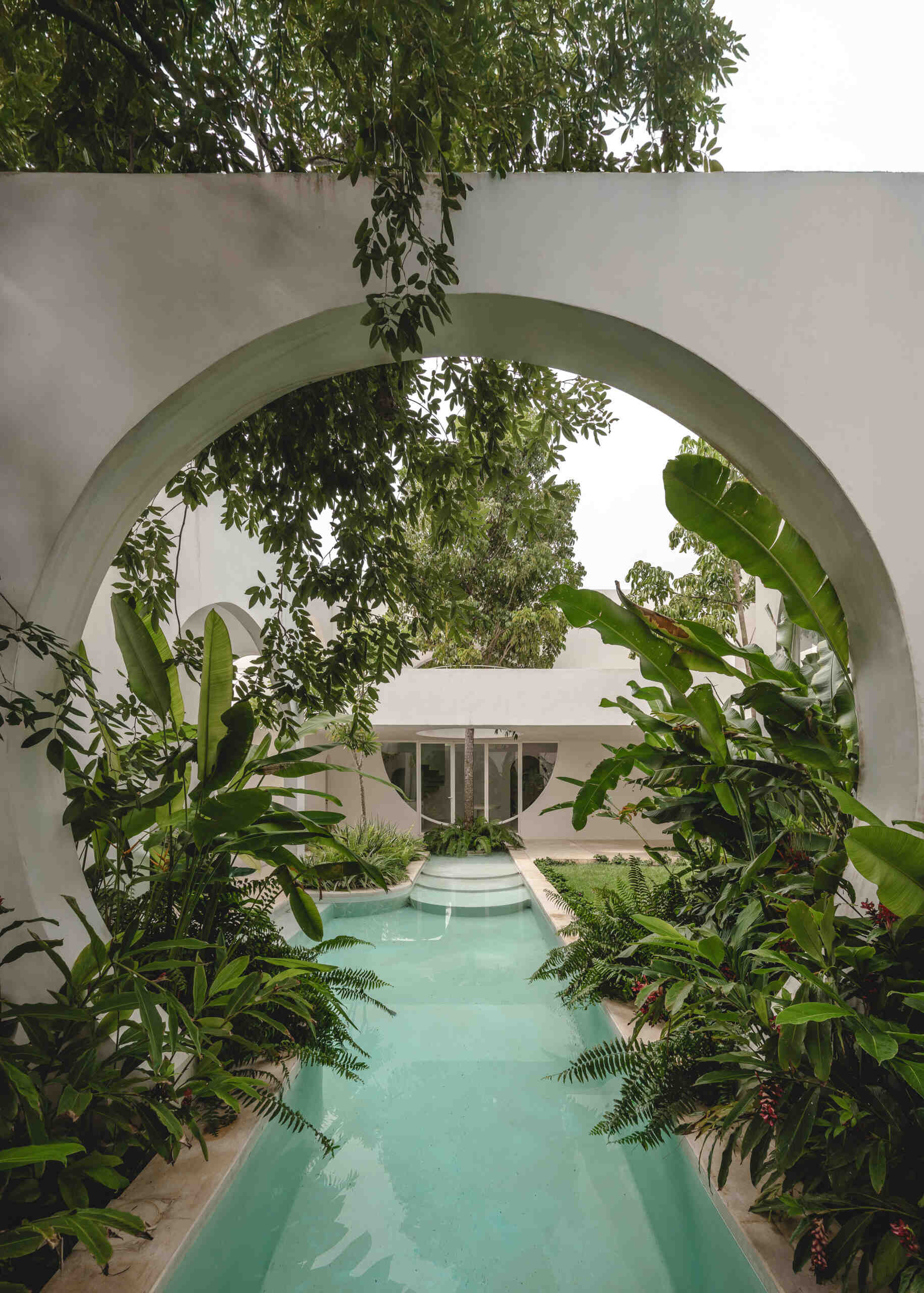 Eclipse House in Mérida, Mexico, is a striking exploration of geometry, light, and landscape. Designed by Etea and Ghostframe, the home features a dramatic double-height gallery, arch-lined walkways, circular openings that inspired its name, and lush gardens woven throughout the architecture.
