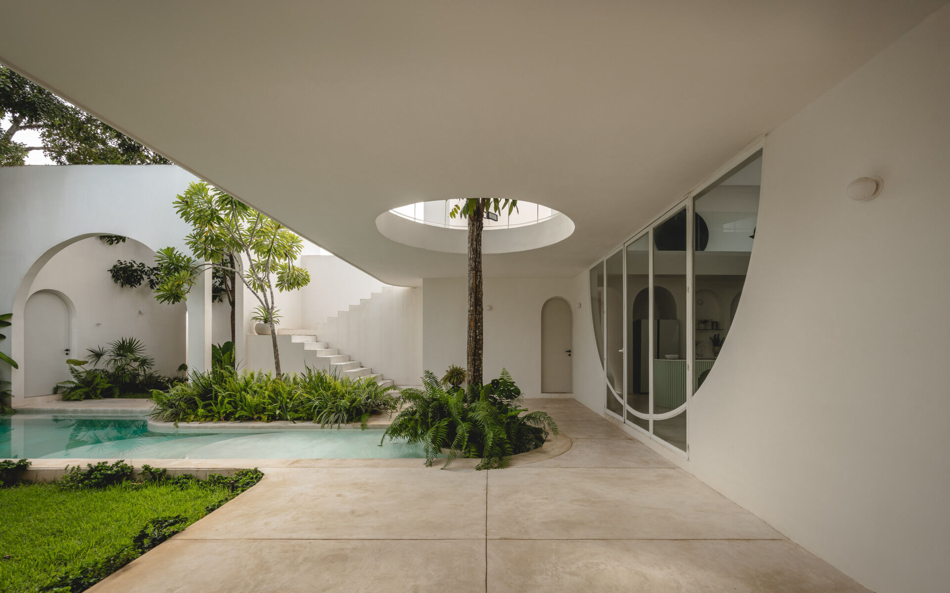 Eclipse House in Mérida, Mexico, is a striking exploration of geometry, light, and landscape. Designed by Etea and Ghostframe, the home features a dramatic double-height gallery, arch-lined walkways, circular openings that inspired its name, and lush gardens woven throughout the architecture.