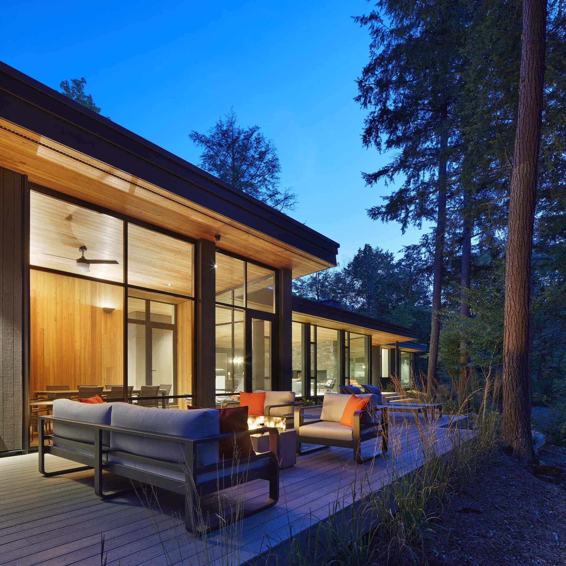 The deck, located off the screened porch, looks out towards the lake. Light gray outdoor furniture keeps the seating area soft and casual, with orange pillows adding just the right pop of color. Tall grasses along the edge help the deck settle into the landscape.