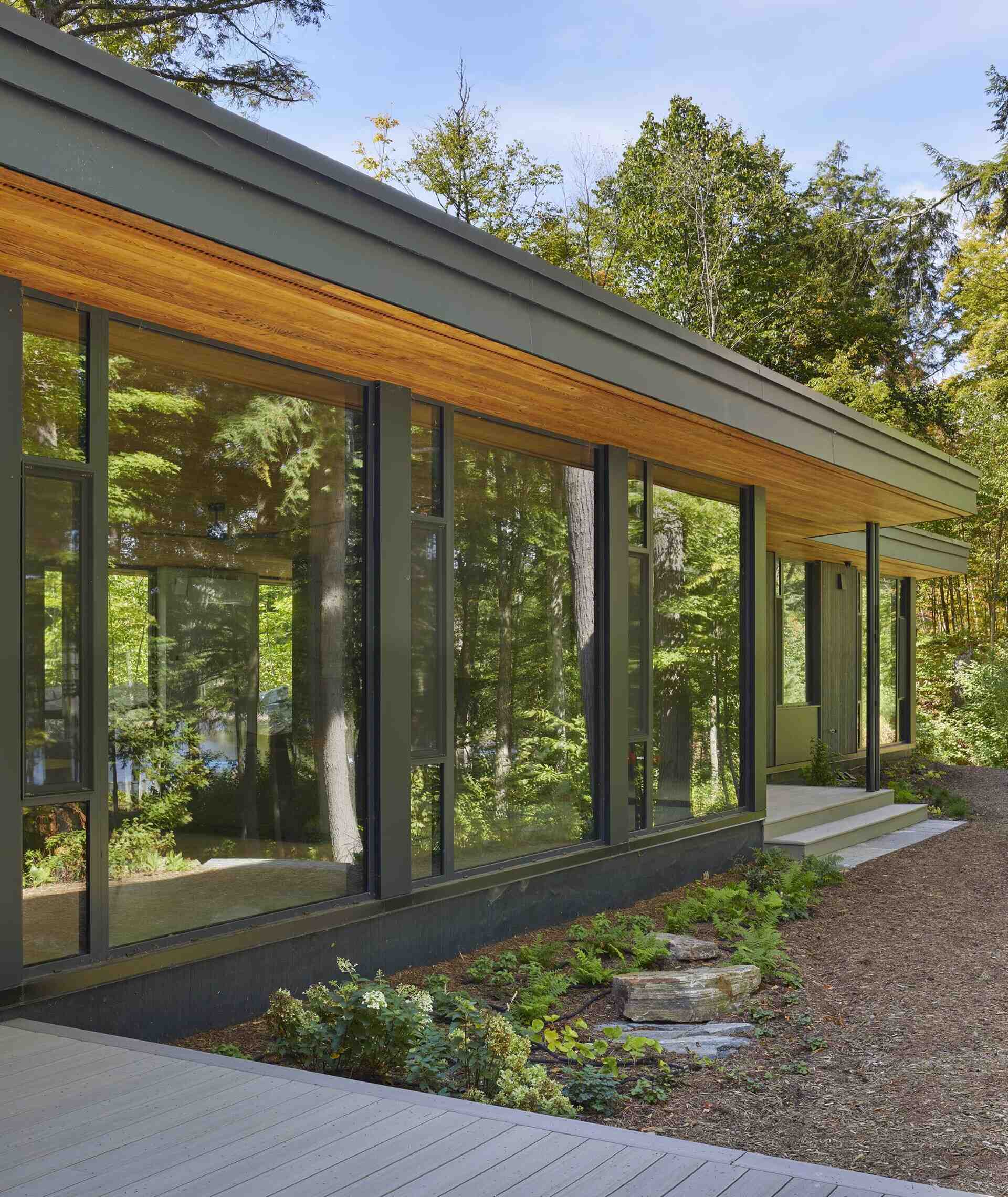 A modern lakeside cottage with walls of windows.