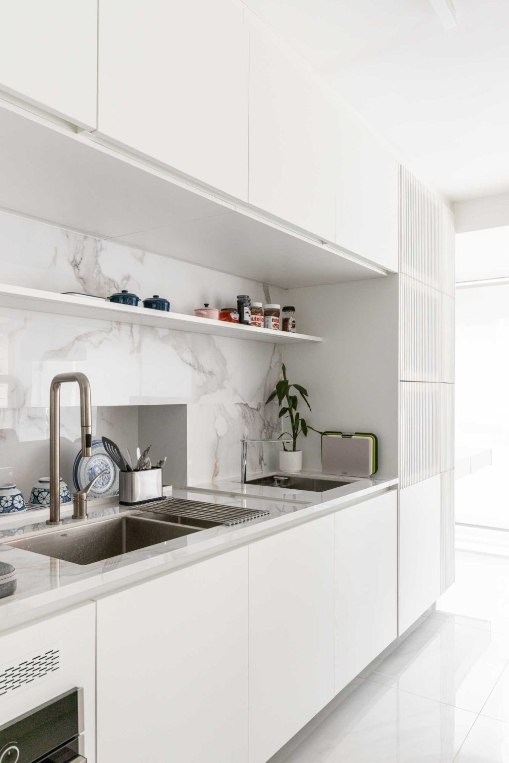 This open-plan kitchen combines warm wood finishes, integrated appliances, and a large island with a dining table designed for conversation.