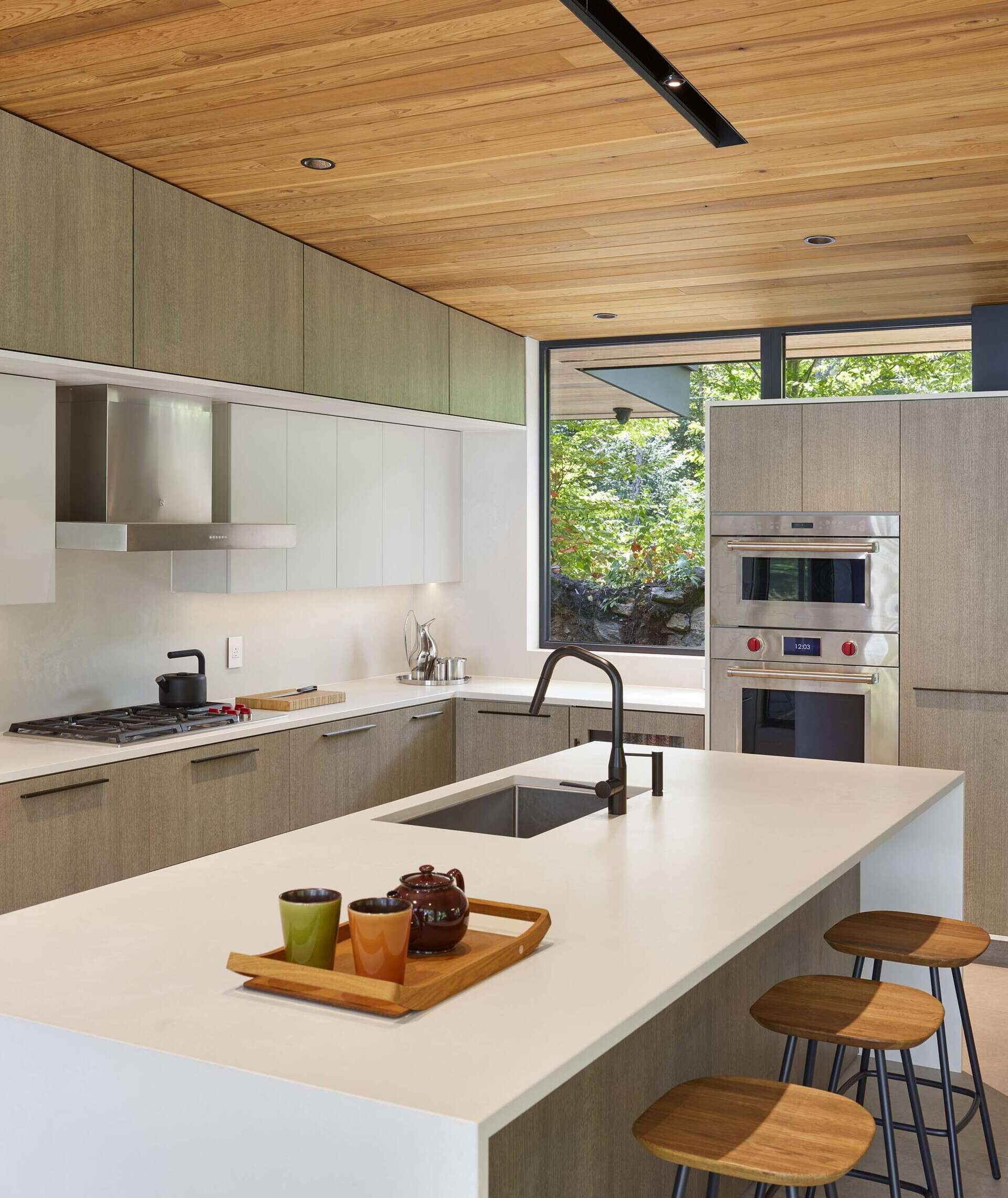 The kitchen, with its pale wood and white cabinetry, and matching island, is integrated into the central great room alongside the living and dining areas.
