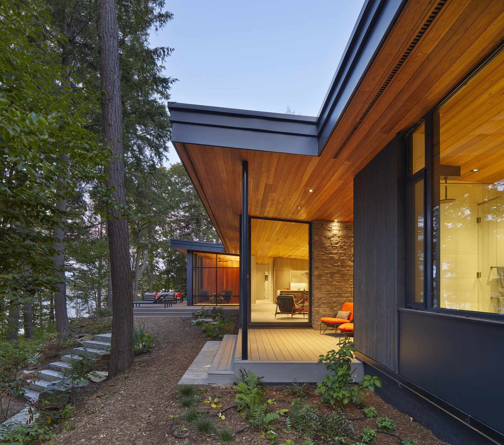 Dark timber cladding, floor-to-ceiling lake views, and warm Douglas fir ceilings create a striking lakeside cottage that blends architecture with its forest setting.