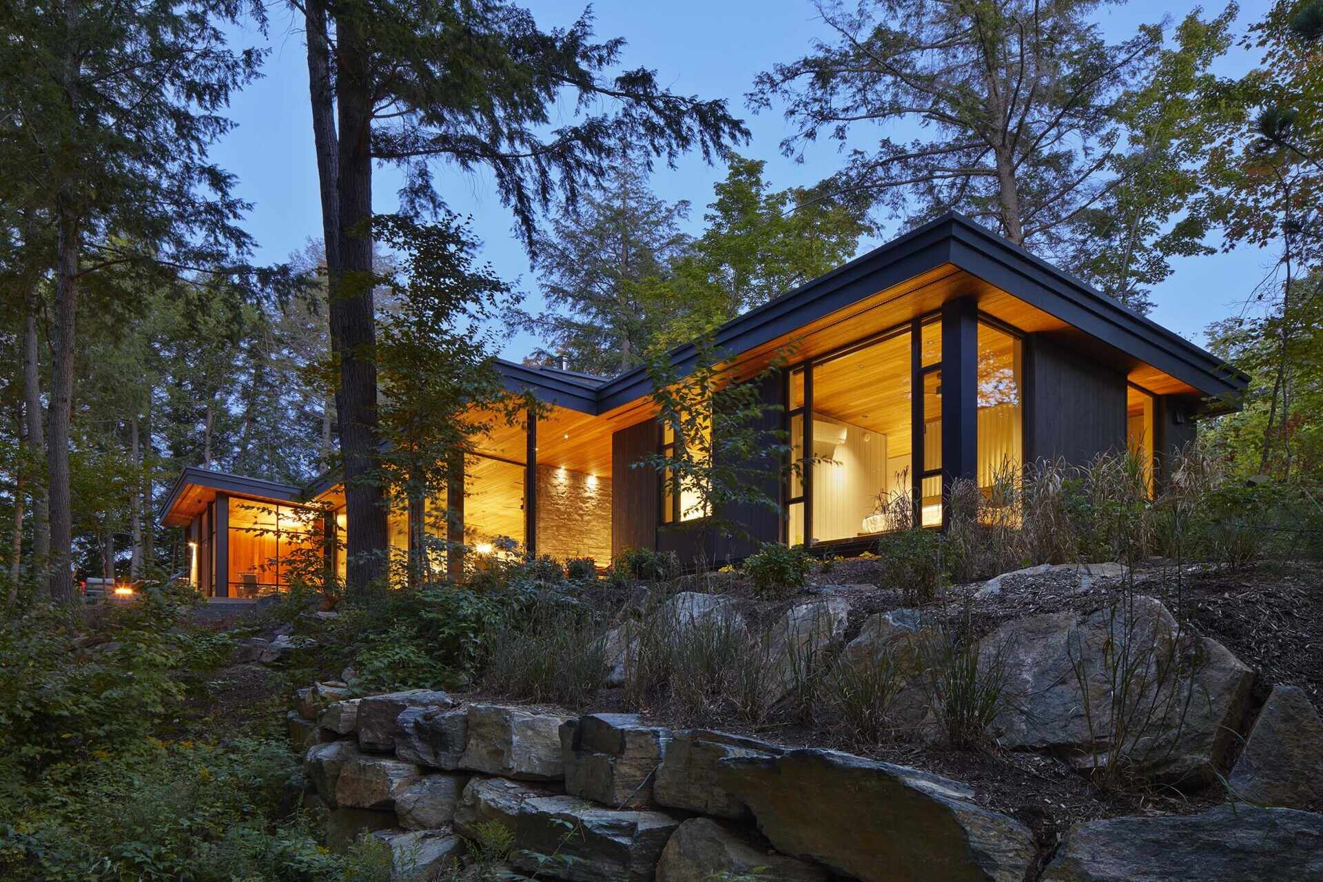 Dark timber cladding, floor-to-ceiling lake views, and warm Douglas fir ceilings create a striking lakeside cottage that blends architecture with its forest setting.