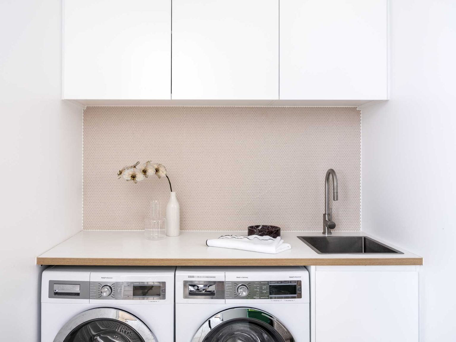In this laundry room, a countertop stretches across the washing machine and dryer, creating a convenient folding area, while cabinetry provides valuable storage.