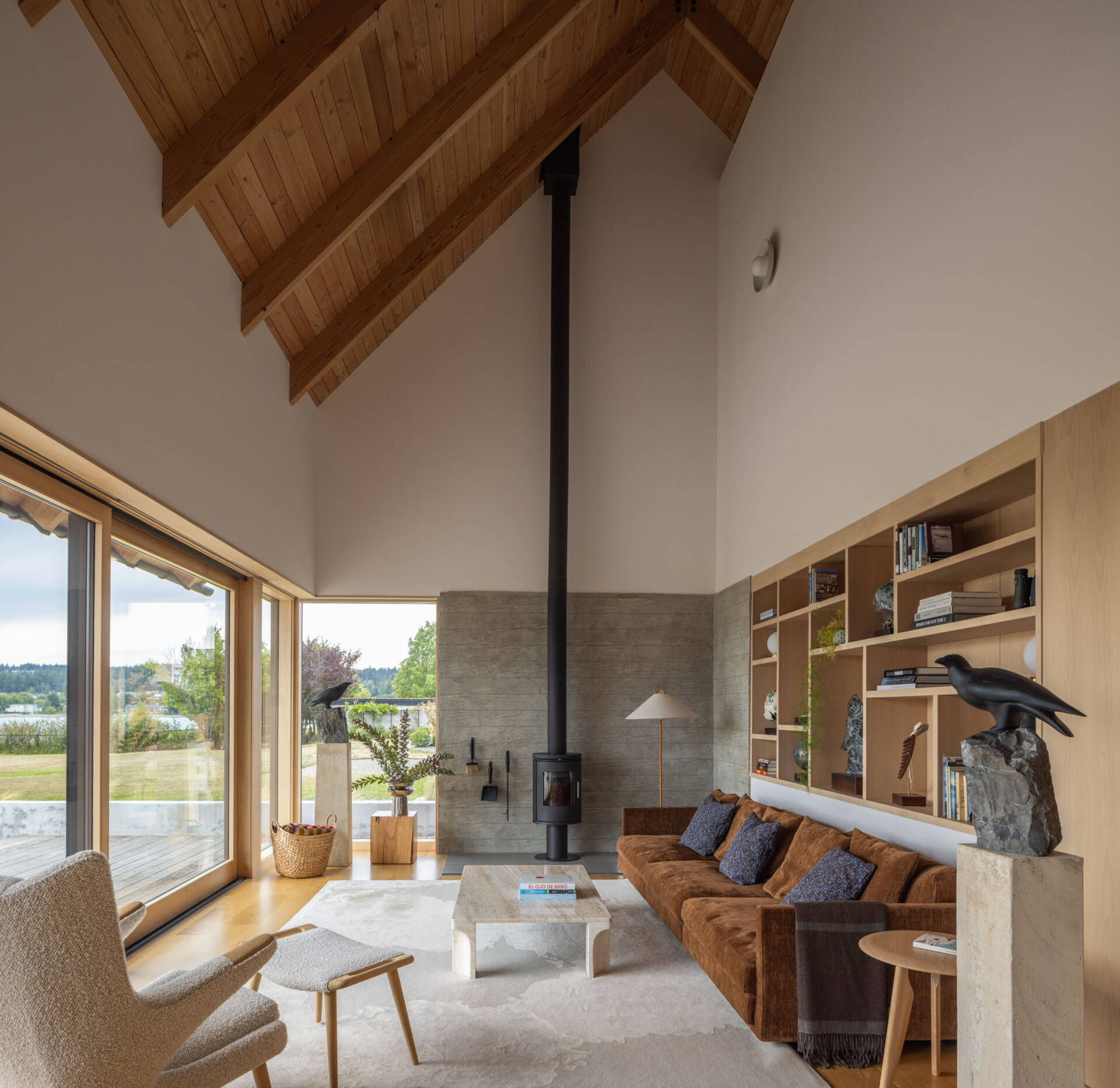Vaulted ceilings, expansive glazing, and waterfront views define this bright living room overlooking Dyes Inlet.