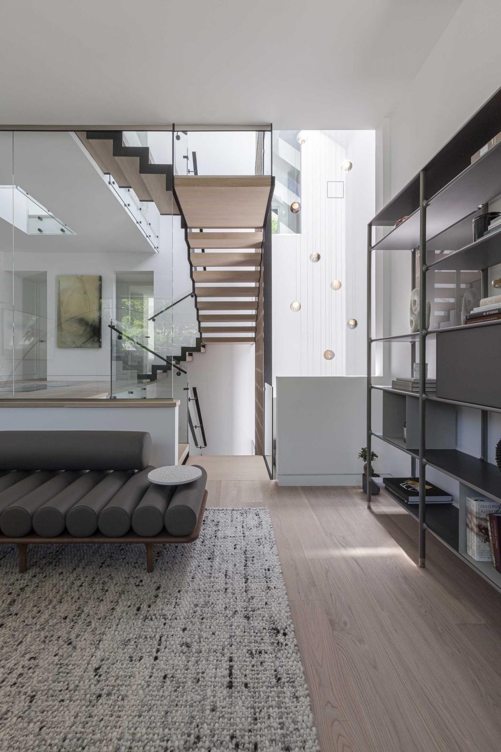 Inside Stack House, multiple living areas offer different experiences, from a bookshelf-lined lounge to a cozy fireplace setting. The flowing layout creates visual connections throughout the home.