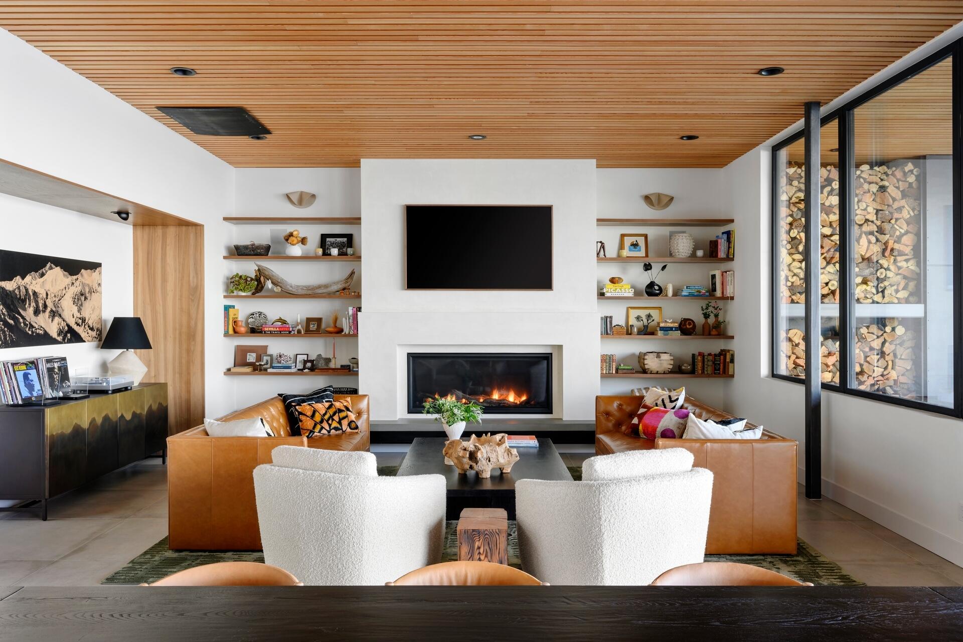 Explore the warm and inviting living room at Lantern House, where a statement fireplace, timber ceiling, and floor-to-ceiling glazing create the perfect place to gather.
