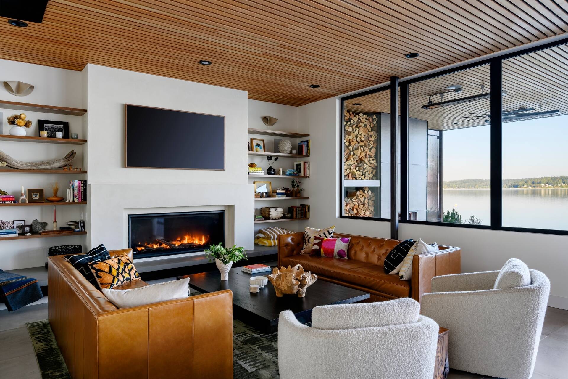 Explore the warm and inviting living room at Lantern House, where a statement fireplace, timber ceiling, and floor-to-ceiling glazing create the perfect place to gather.