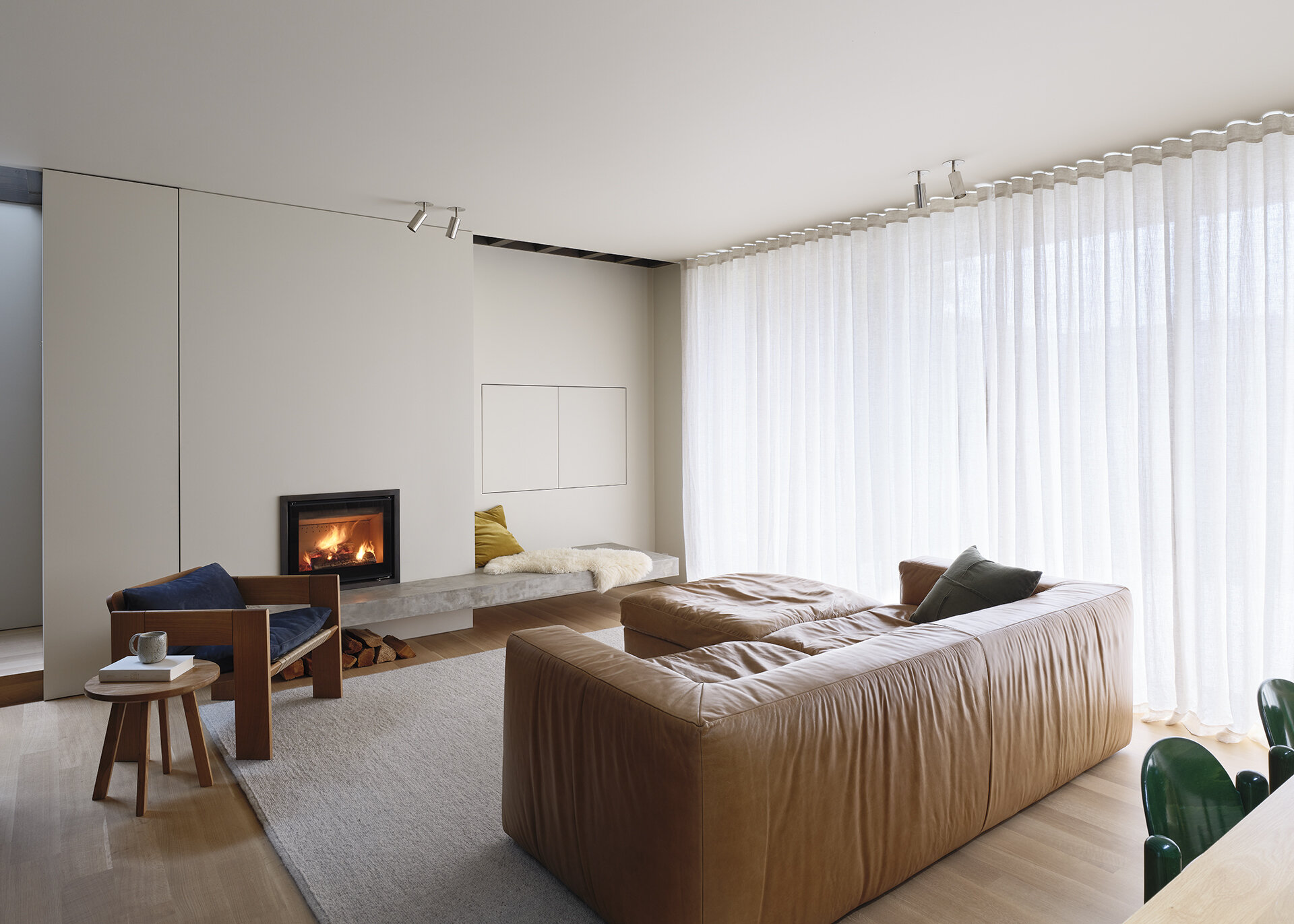 A concrete fireplace hearth becomes built-in seating in this bright living room filled with natural light and garden views.