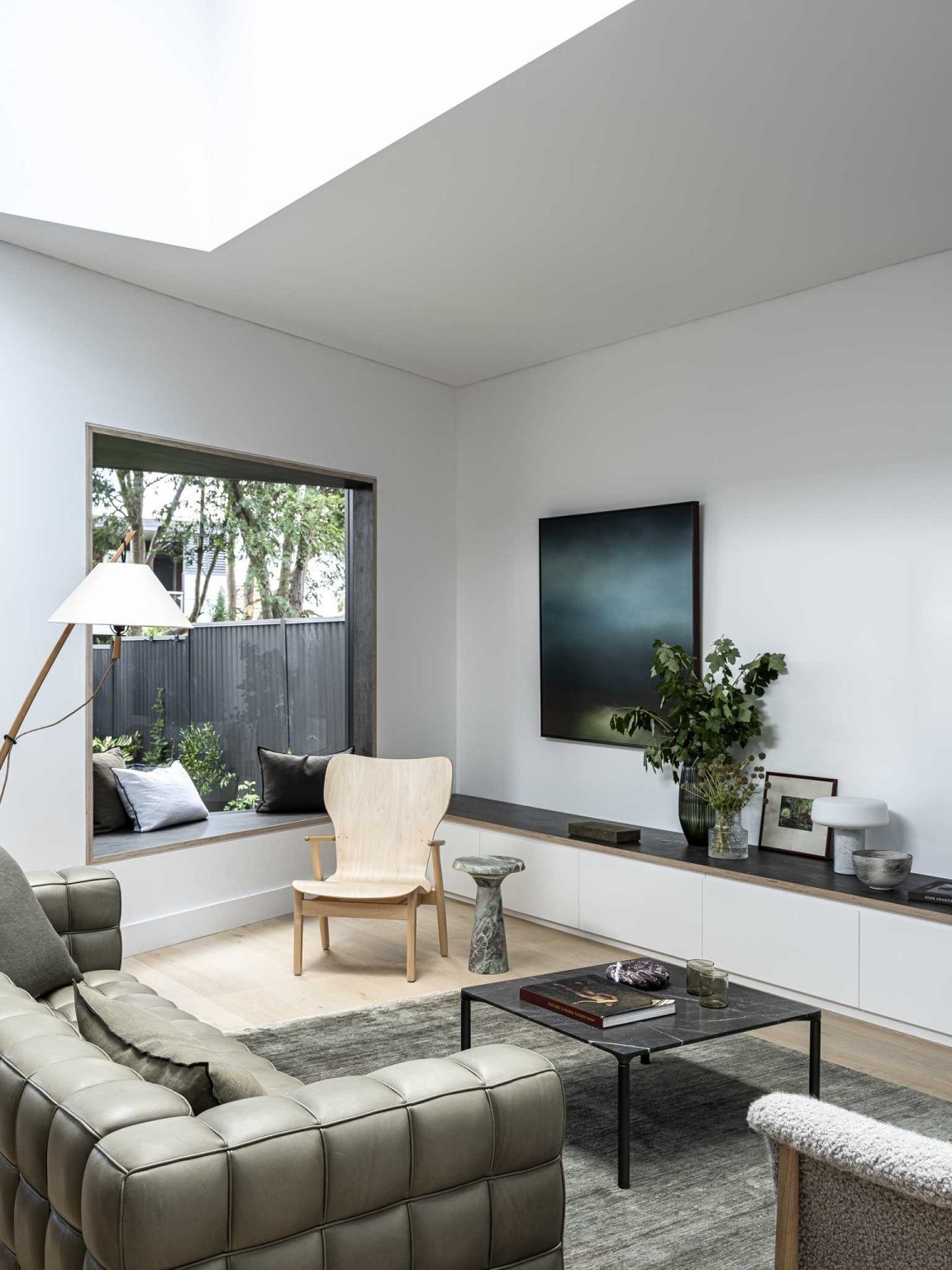 Large skylights, white interiors, and warm timber details fill this open-plan living space with light and character.
