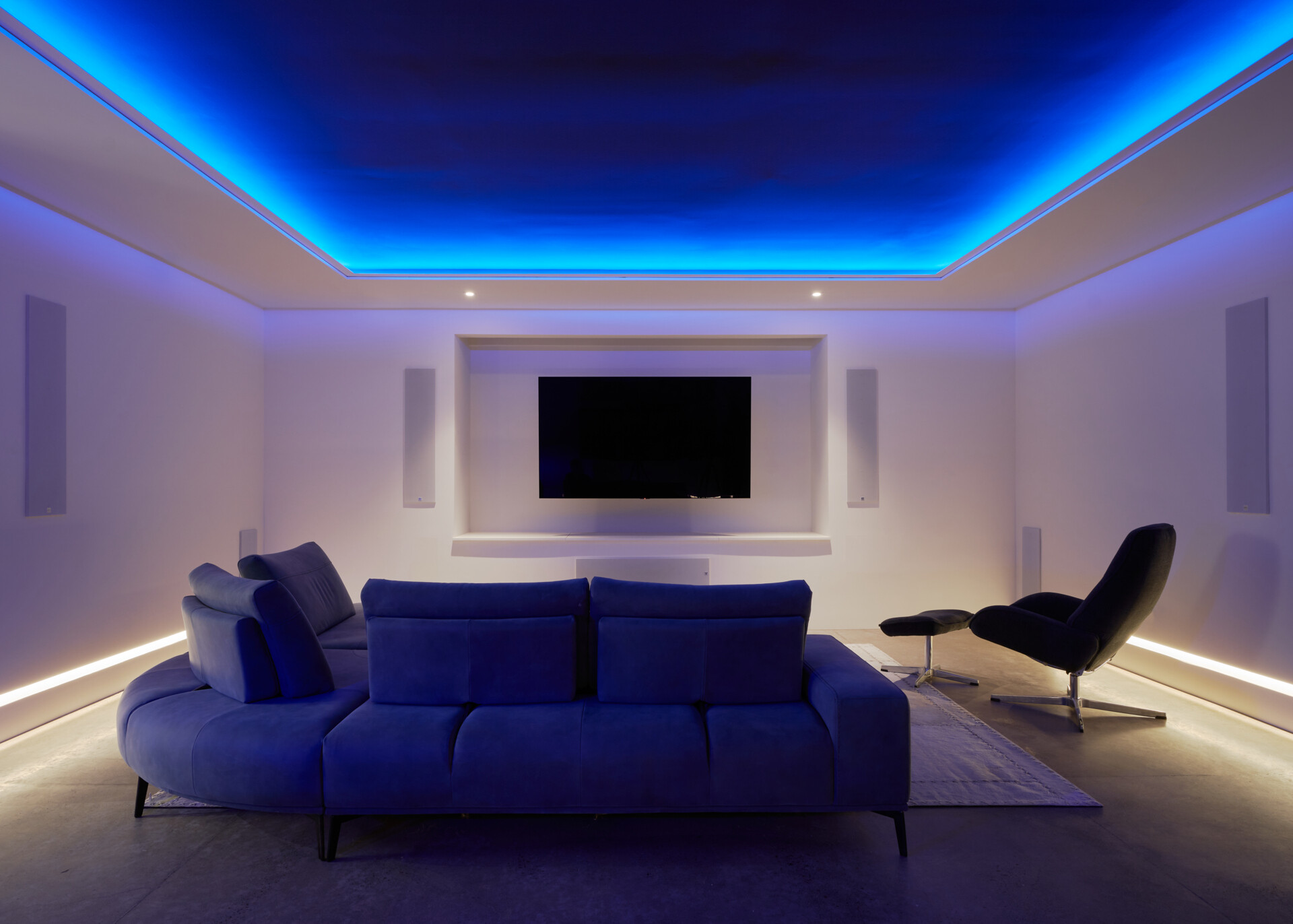 A modern basement media room with hidden lighting.