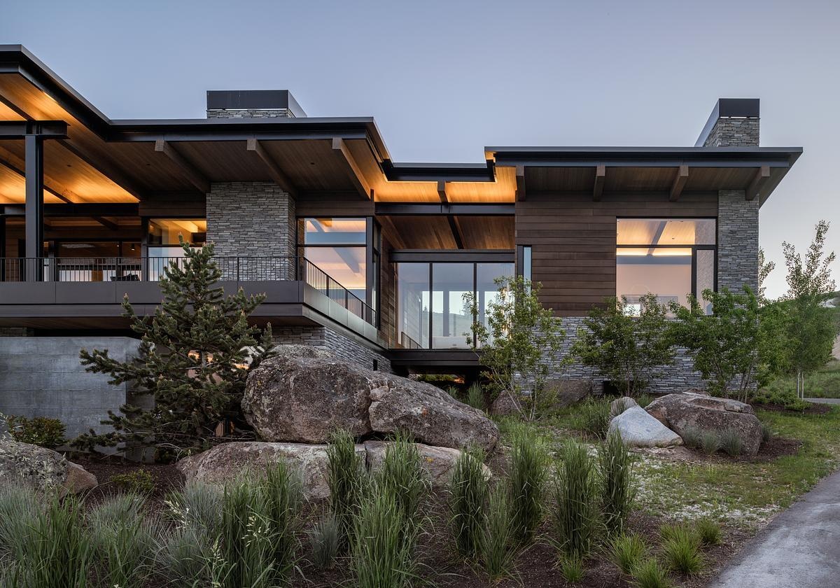 This modern mountain home blends into an Idaho hillside with a living green roof, Oakley stone walls, Douglas fir siding, and expansive glazing that frames mountain views while softening its presence on the landscape.